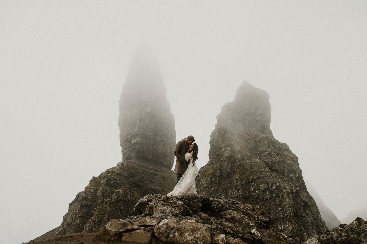 Moody black and white landscape of jagged rock formations emerging through thick highland mist.