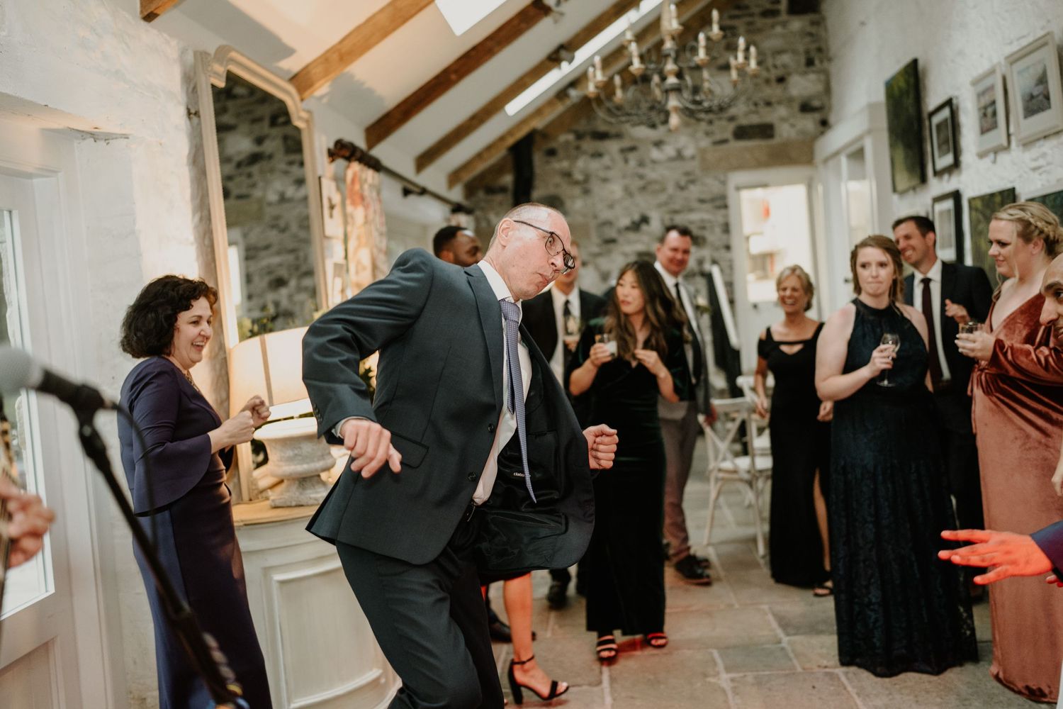 Guests dancing and celebrating at a wedding reception in a rustic stone venue.
