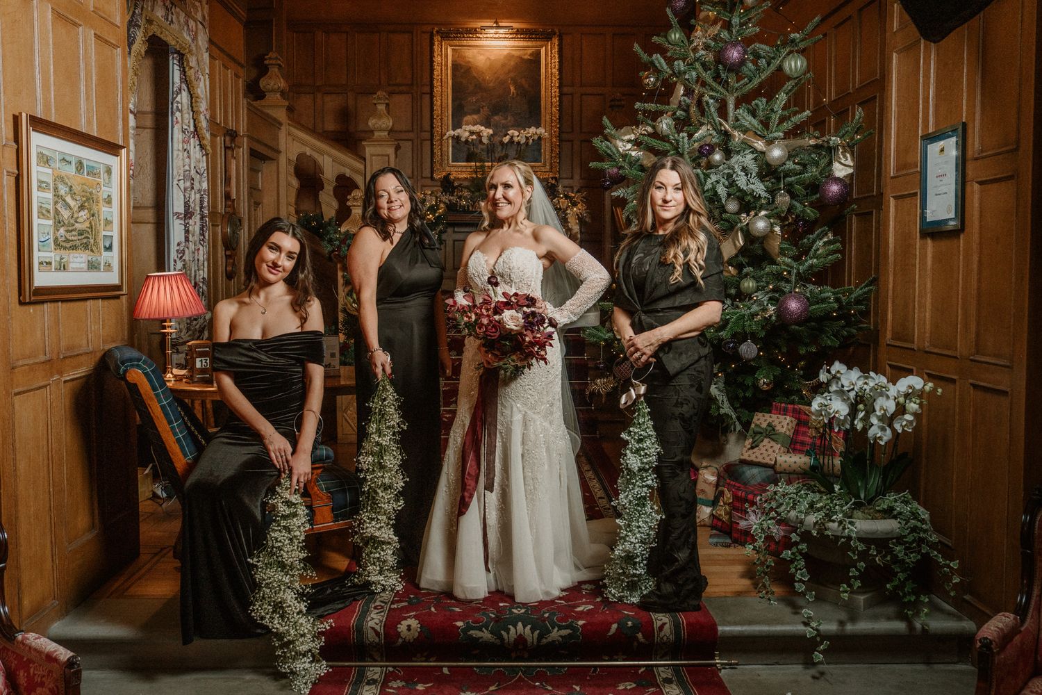 Wedding group photo on vintage staircase with Christmas trees and festive holiday decor.