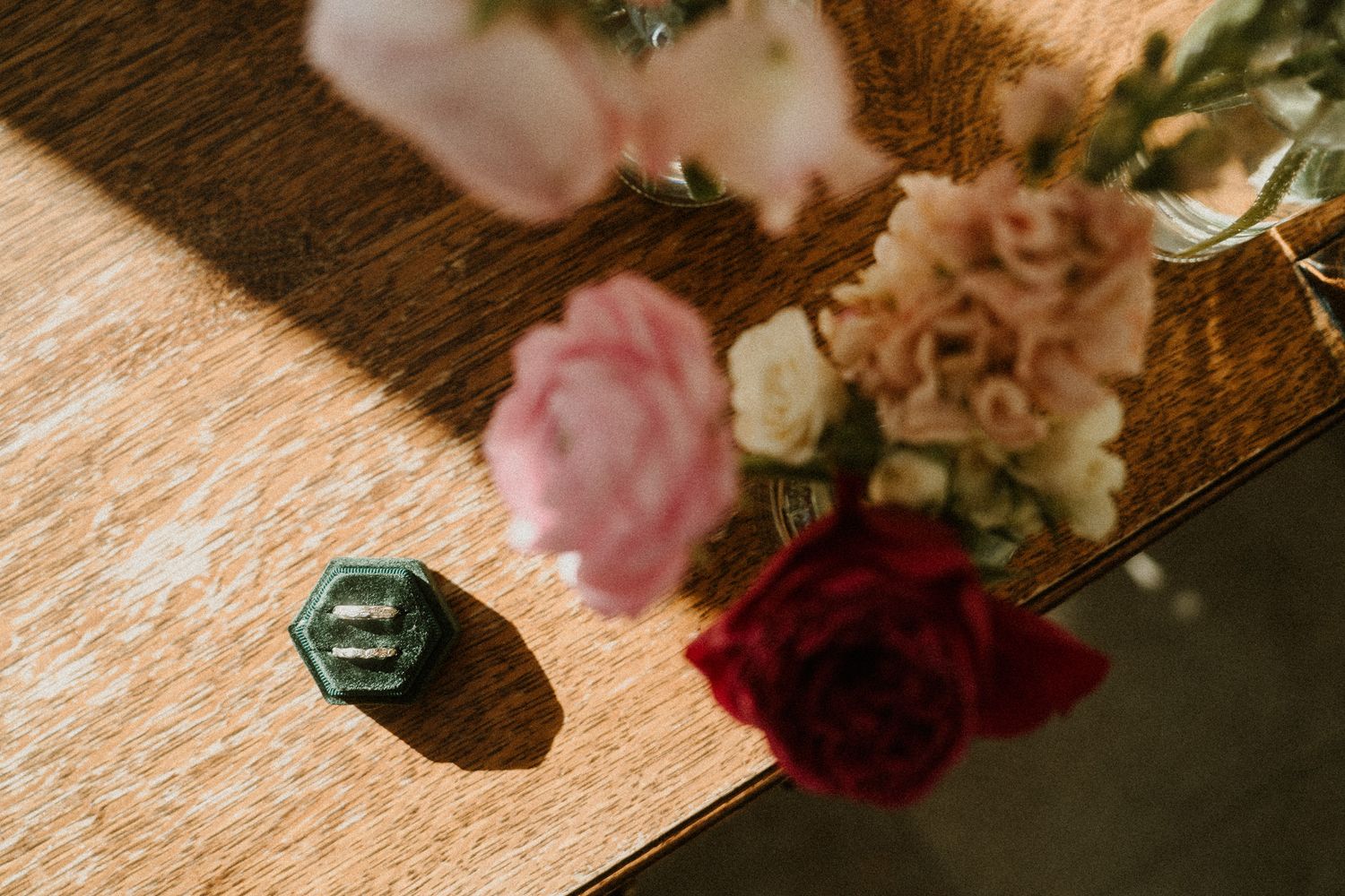 Close-up details of floral arrangements with pink and burgundy blooms on wooden surface.