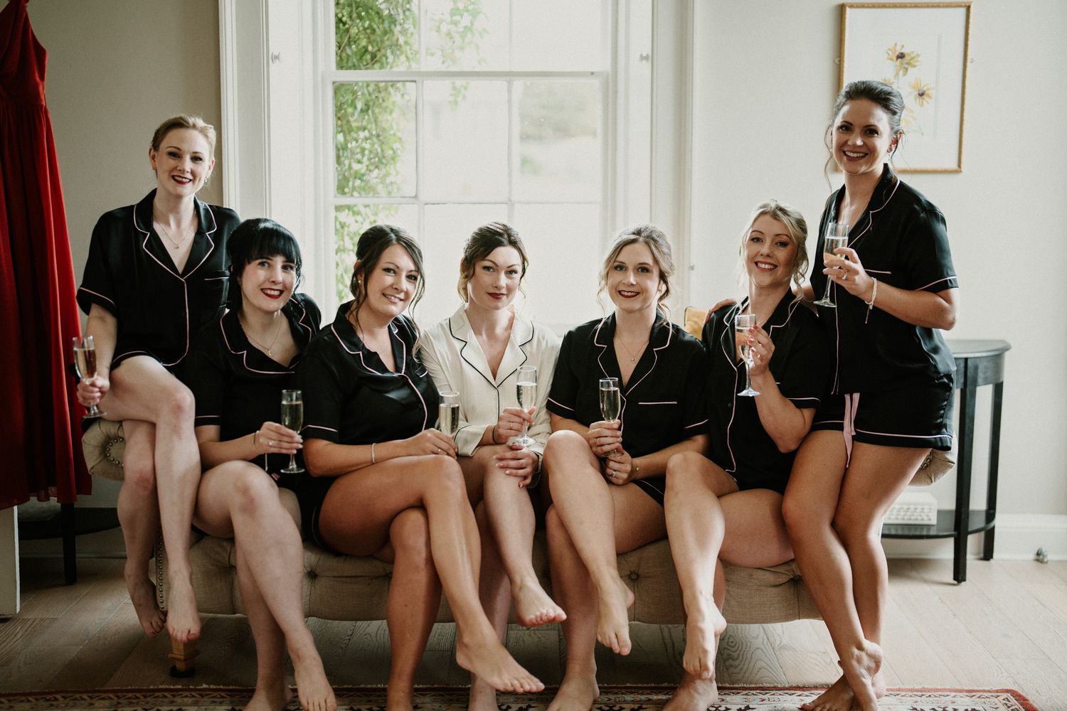 Group in coordinated black and white attire poses on furniture in a sunlit room.