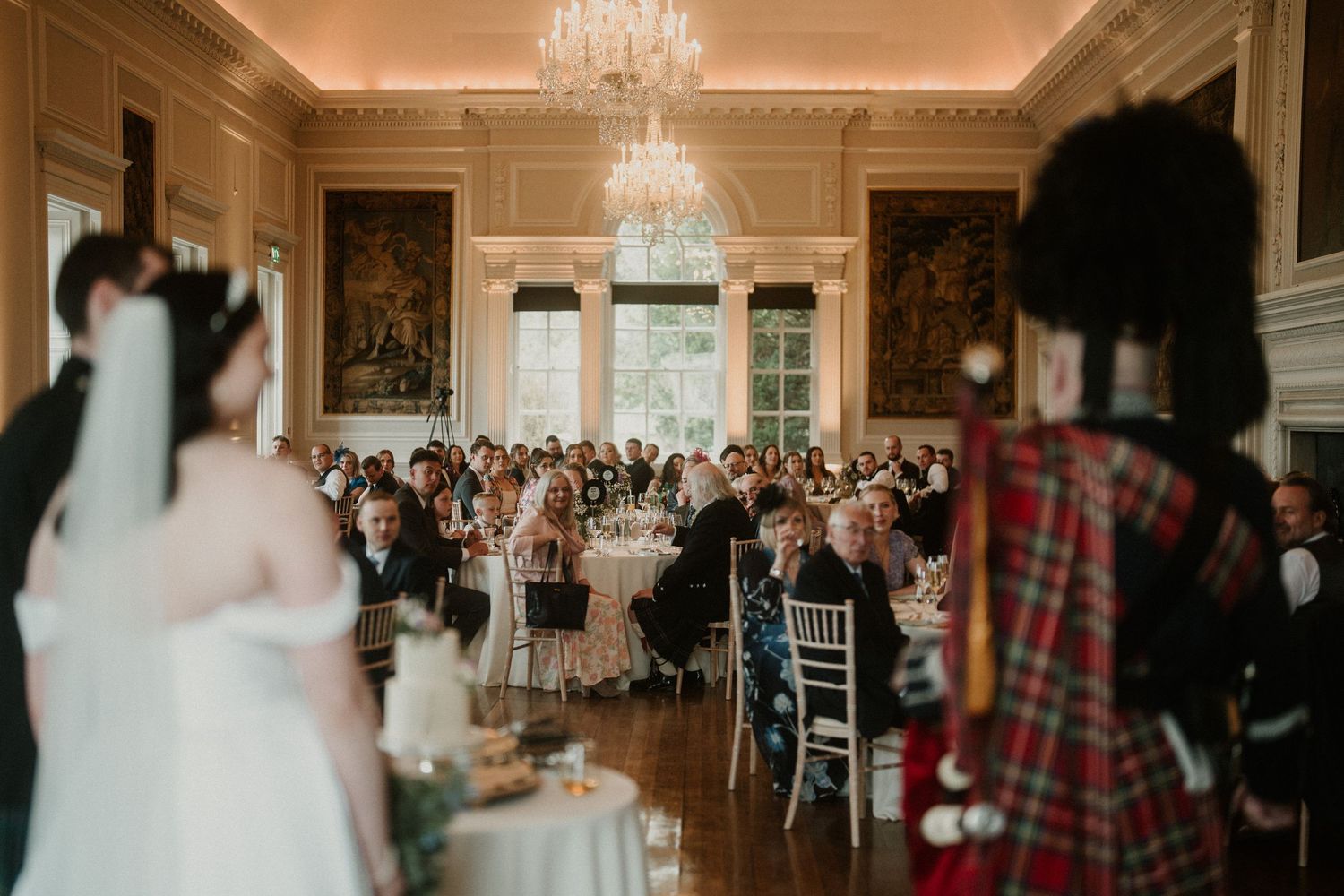 Elegant wedding reception in grand ballroom with crystal chandelier and formal table settings.