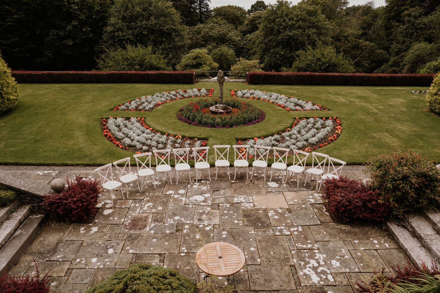 Outdoor wedding ceremony setup with white chairs arranged in a semicircle on a green lawn.