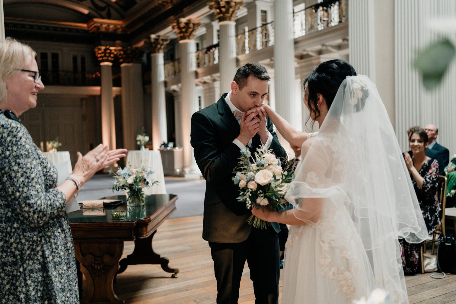 Wedding celebration candid moments in an elegant columned hall.