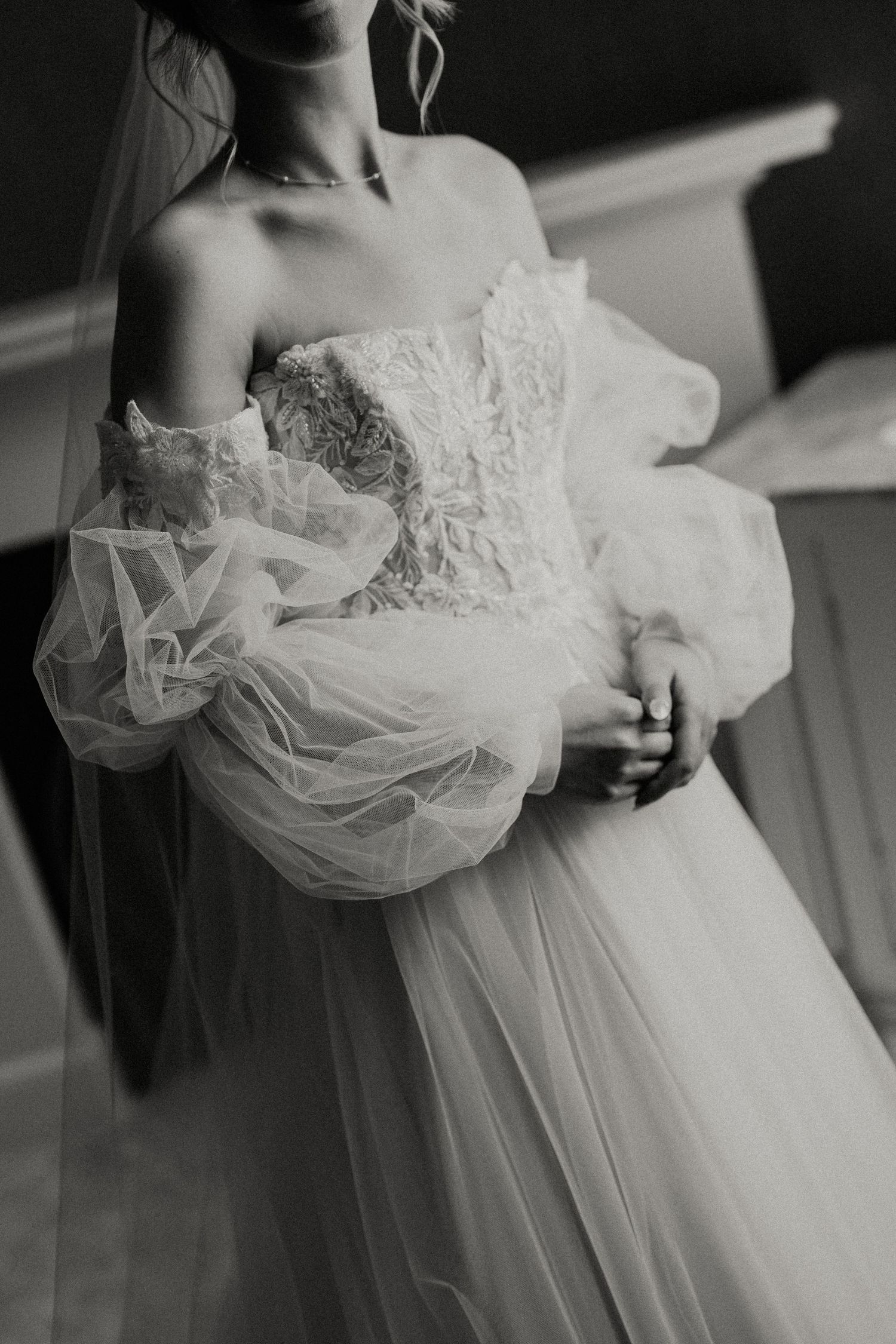Close-up details of delicate lace and tulle on a white wedding dress bodice.
