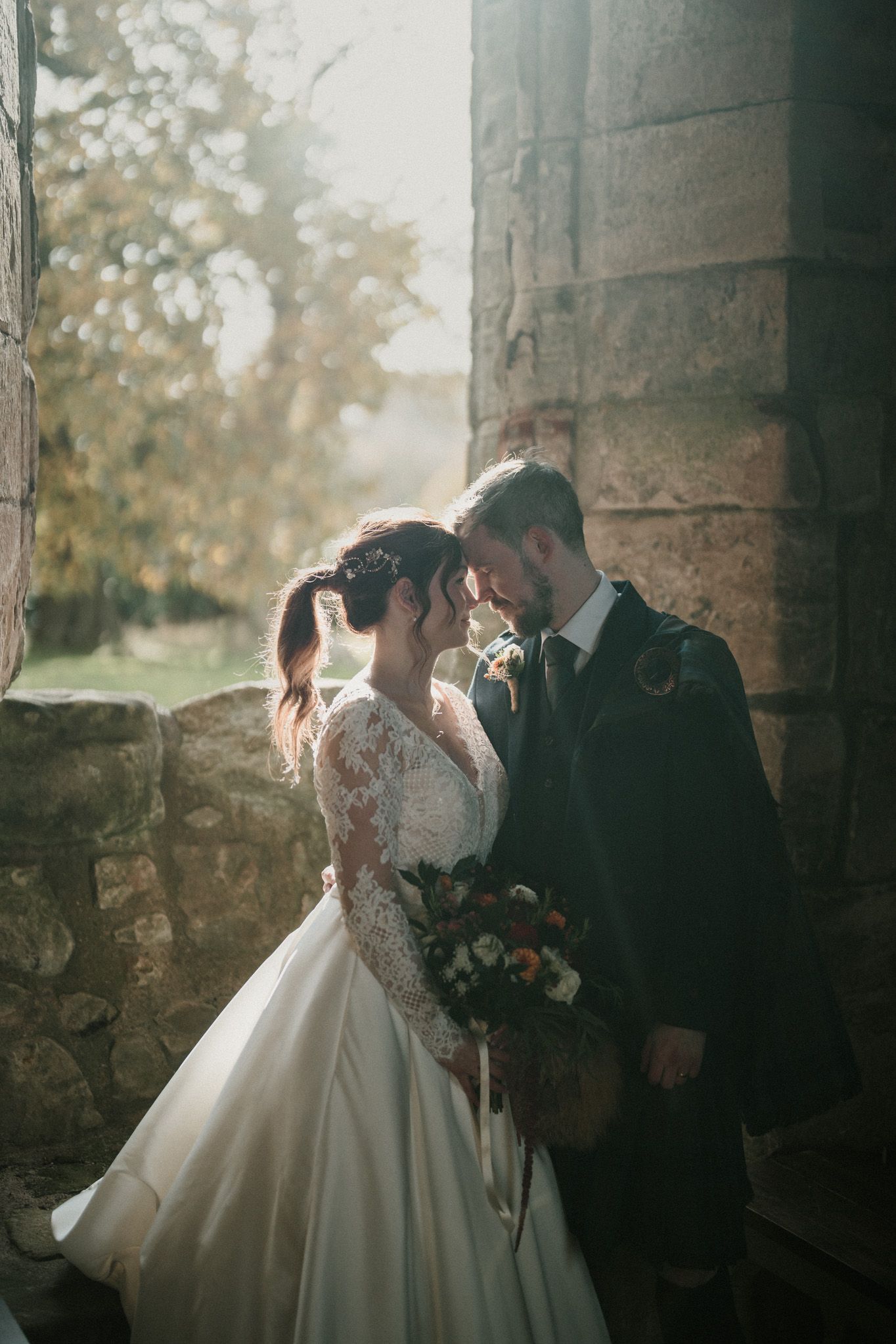 Intimate wedding moments photographed against rustic stone walls and autumn foliage.