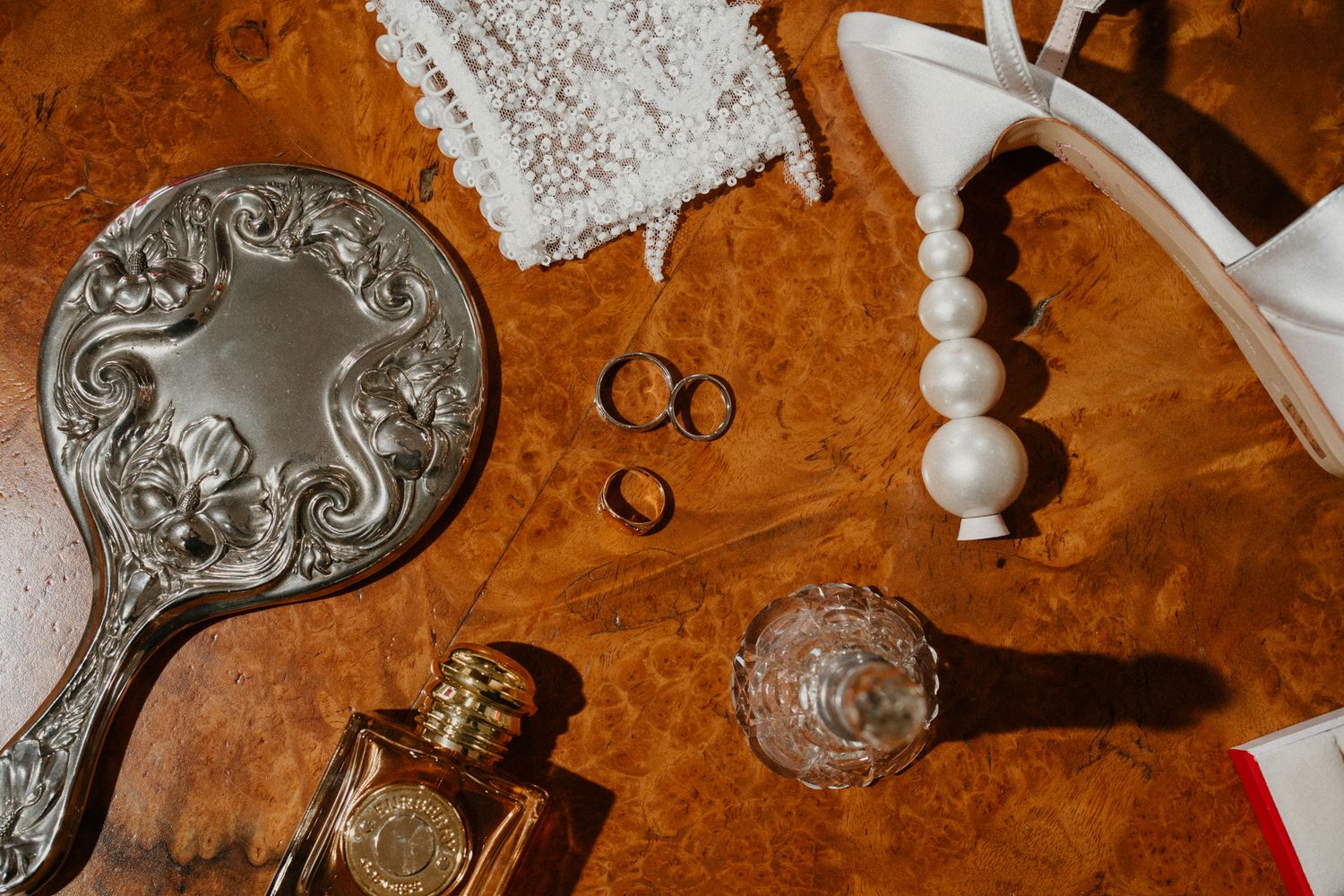 Vintage silver hand mirrors and wedding accessories displayed on a rich brown surface.