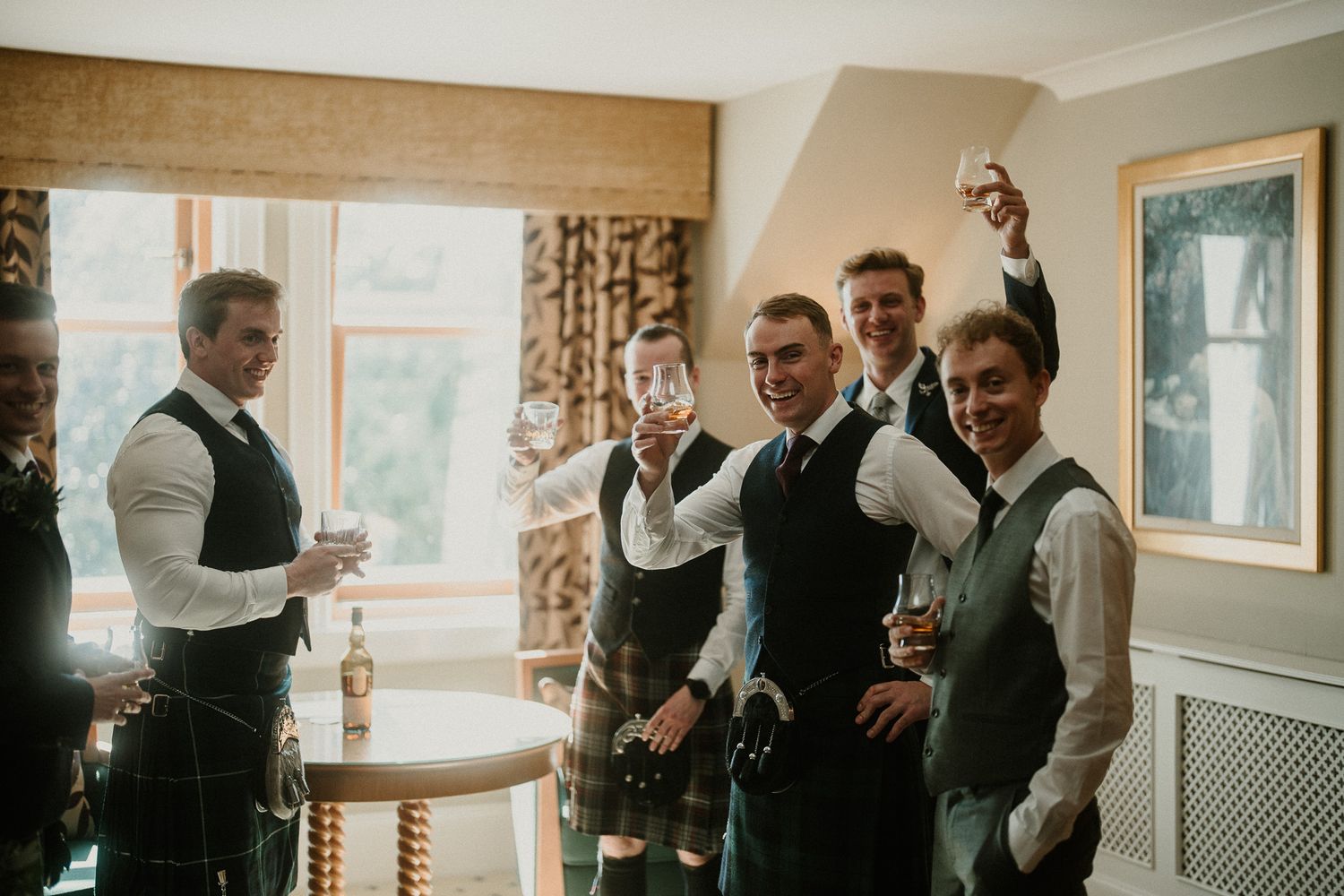 Wedding party members in formal attire gather in an elegant indoor room.
