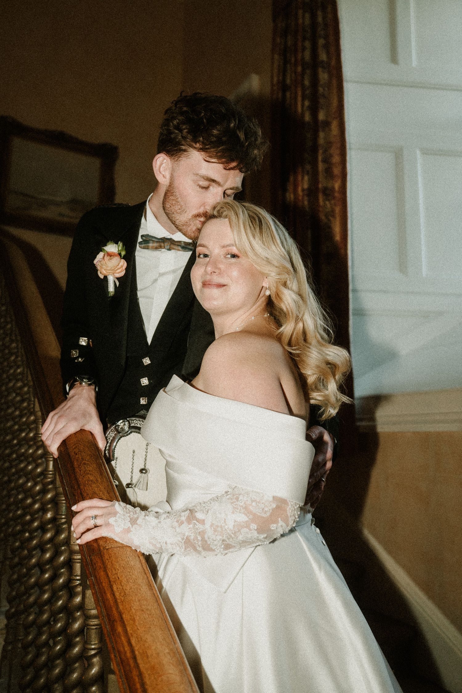 A tender moment between newlyweds on a grand staircase with decorative bannisters.