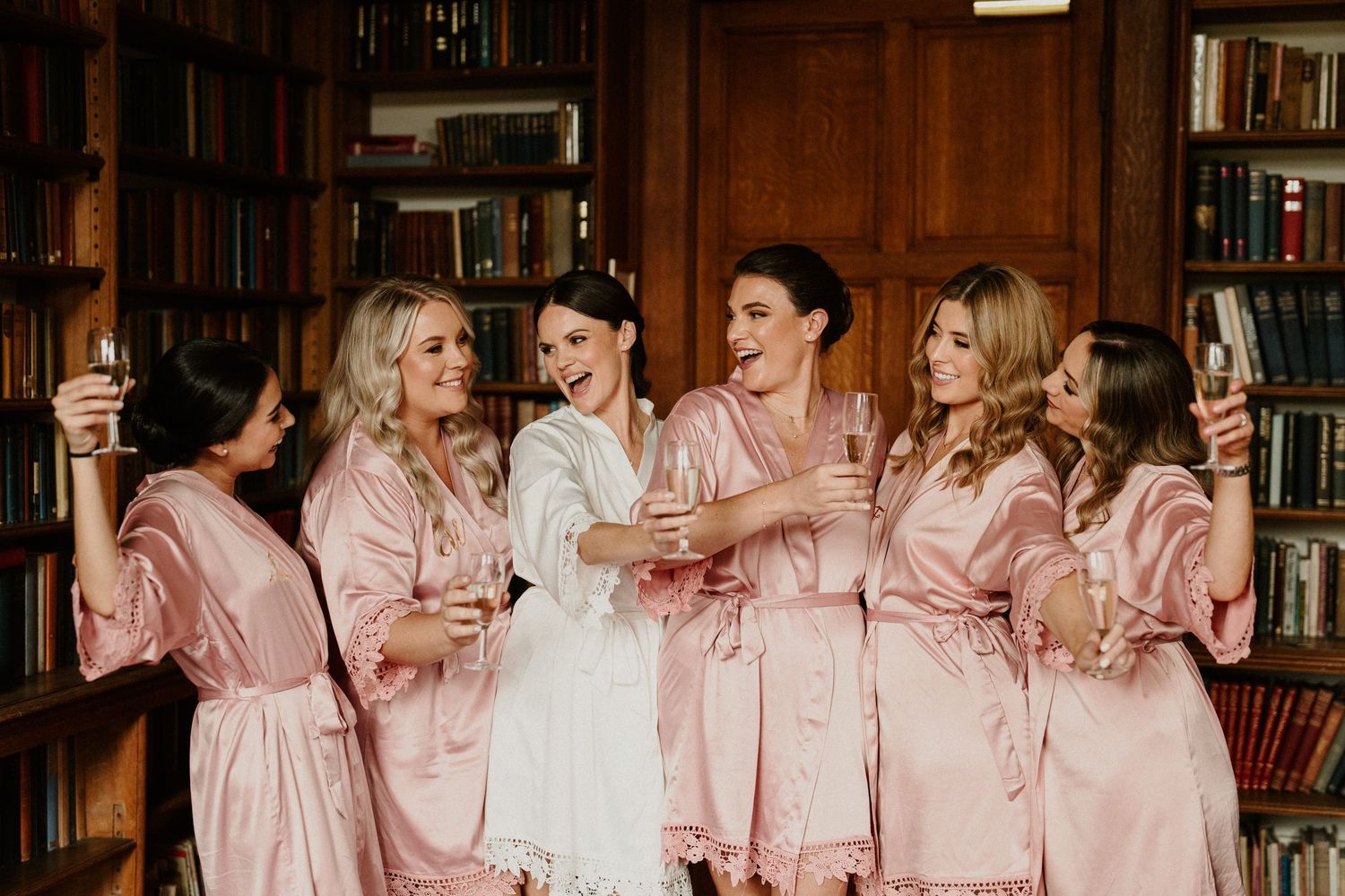 Group celebrating with champagne in matching pink robes.