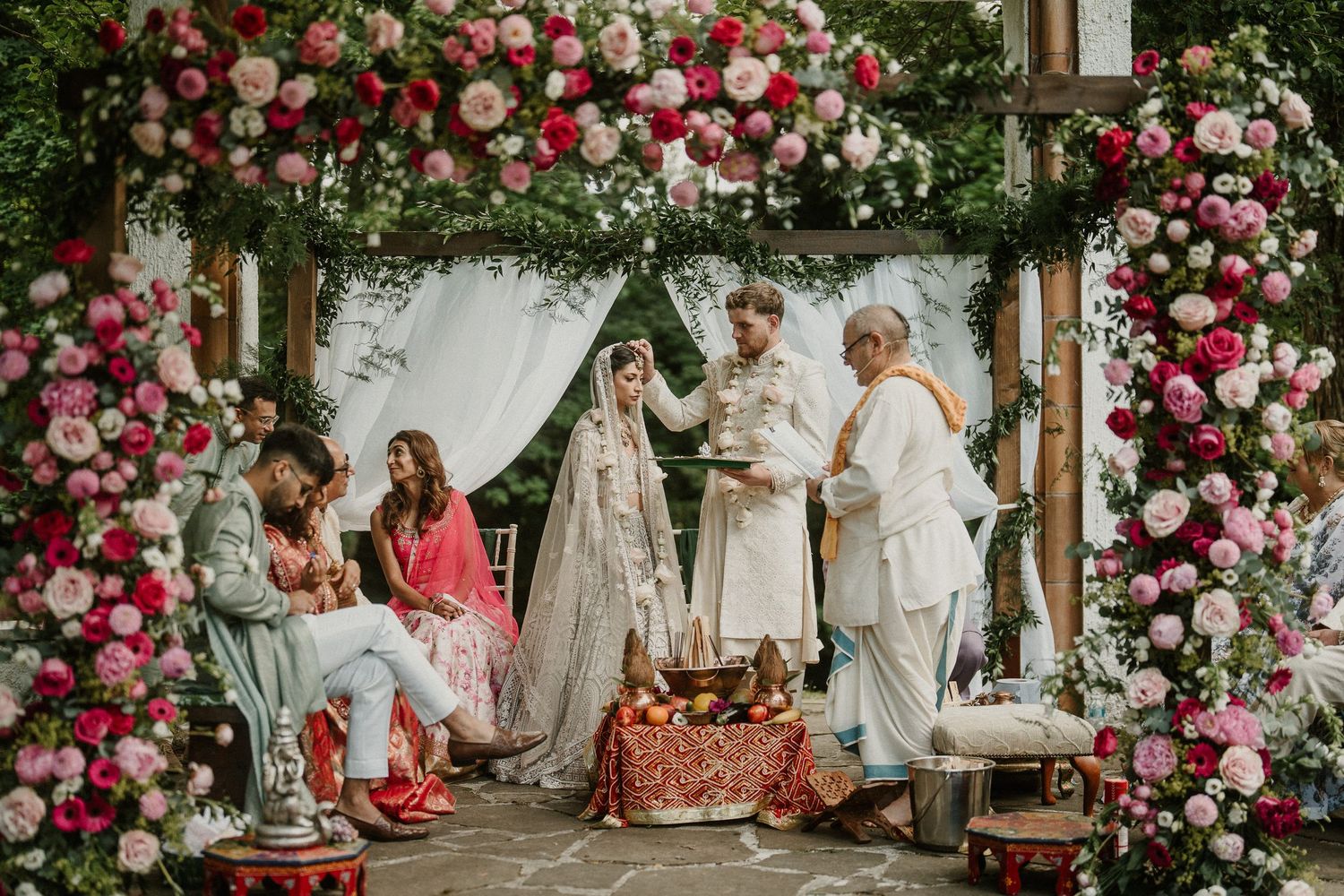 Elegant wedding ceremony setup with pink and white floral arch and white draping creating a romantic atmosphere.