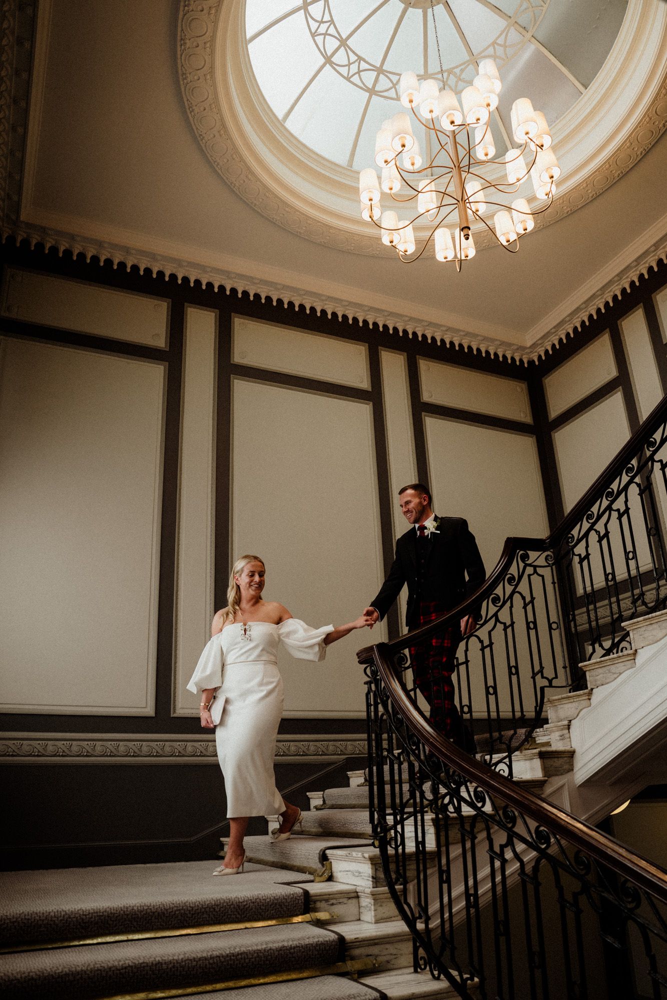 Grand staircase with ornate chandelier and elegant architectural details.