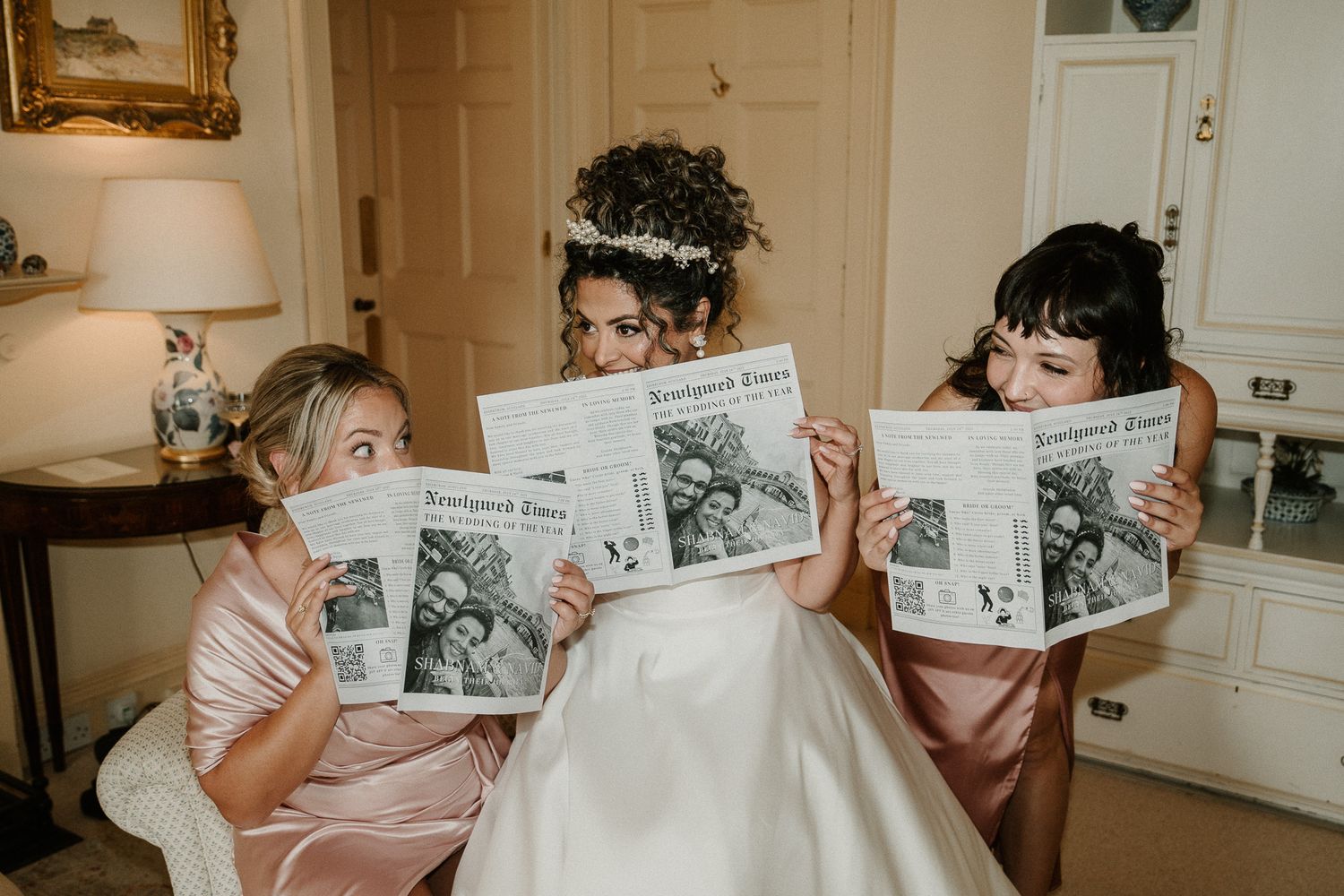 Wedding party holds up black and white photos while sitting in a row.