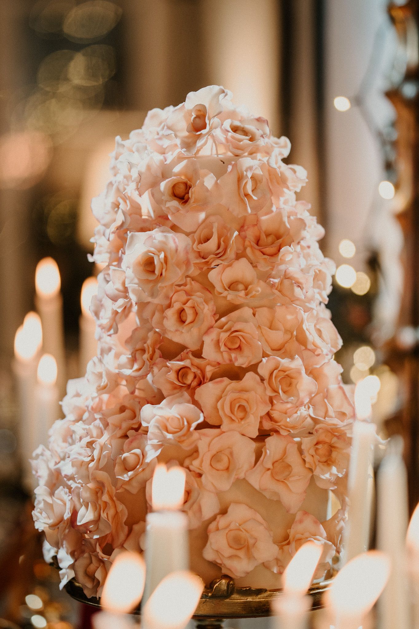 Blush pink rose centerpieces and white taper candles create a romantic table setting.