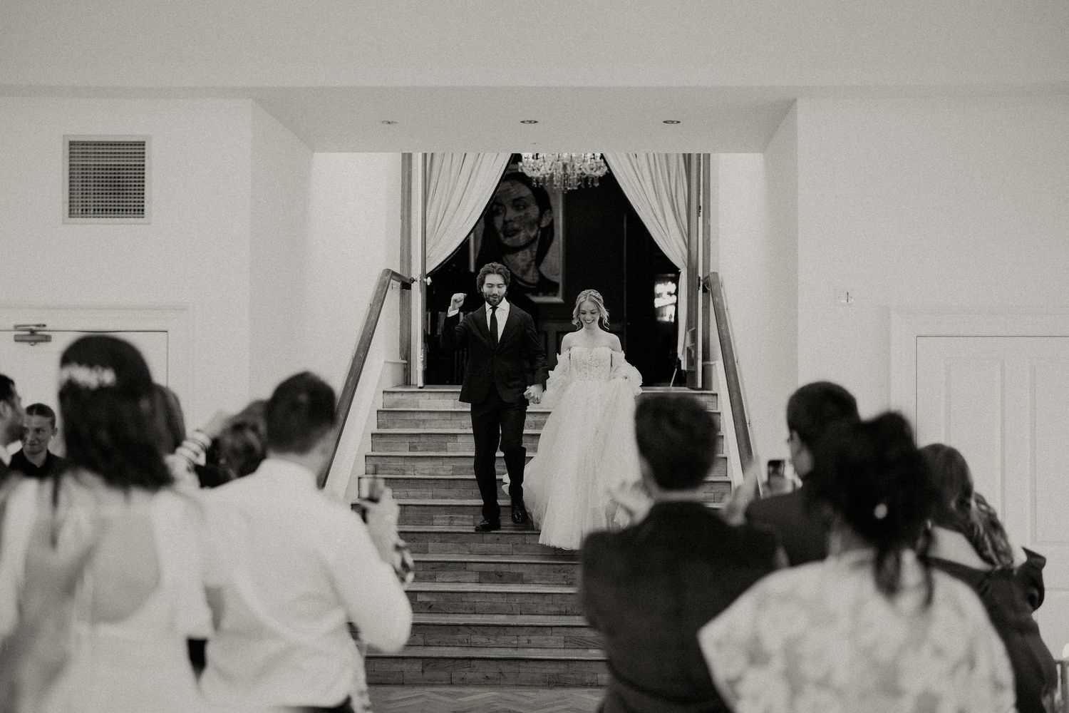 Black and white photo of wedding ceremony procession in elegant indoor venue.