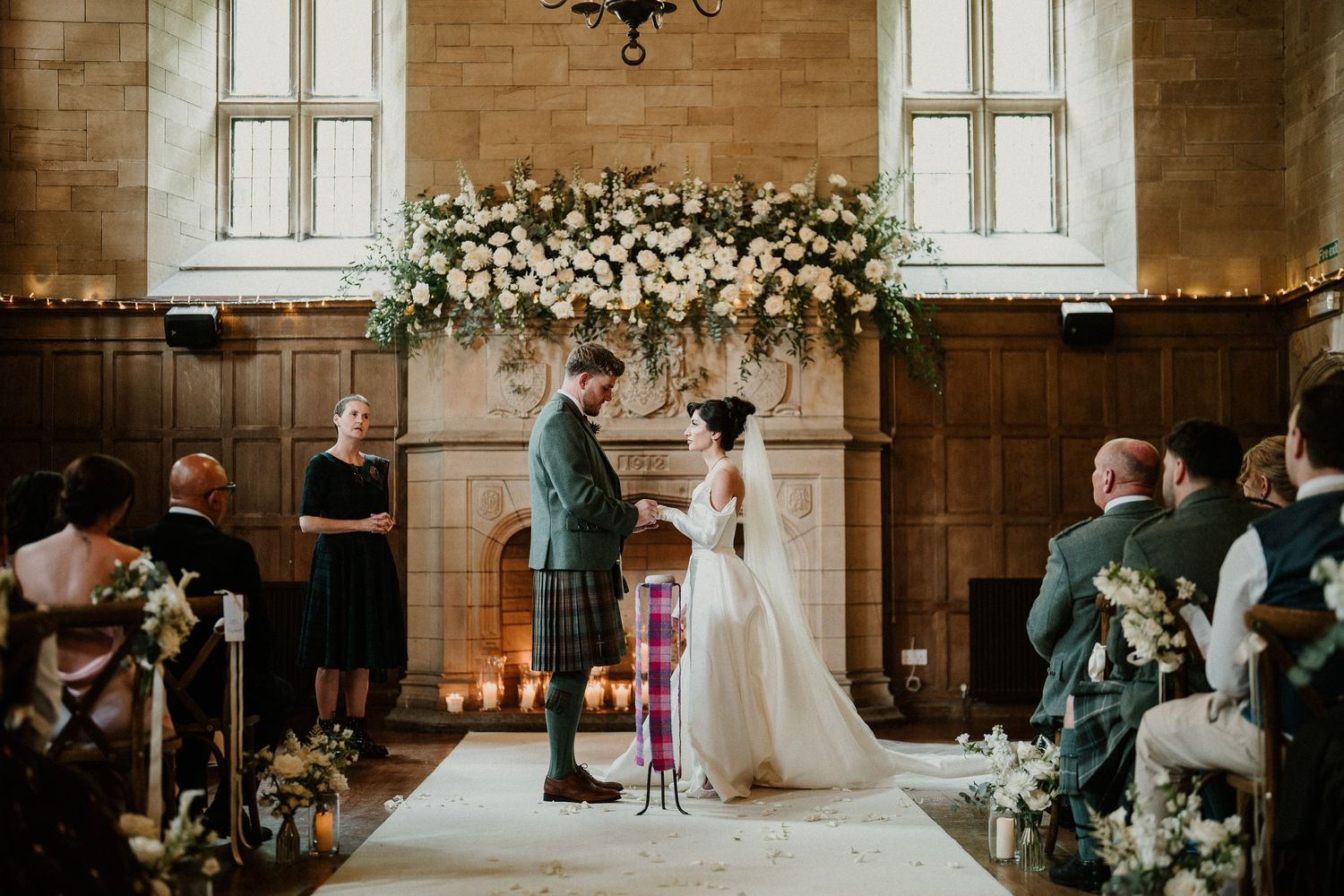 Wedding ceremony at altar with white floral arrangements in historic church setting.