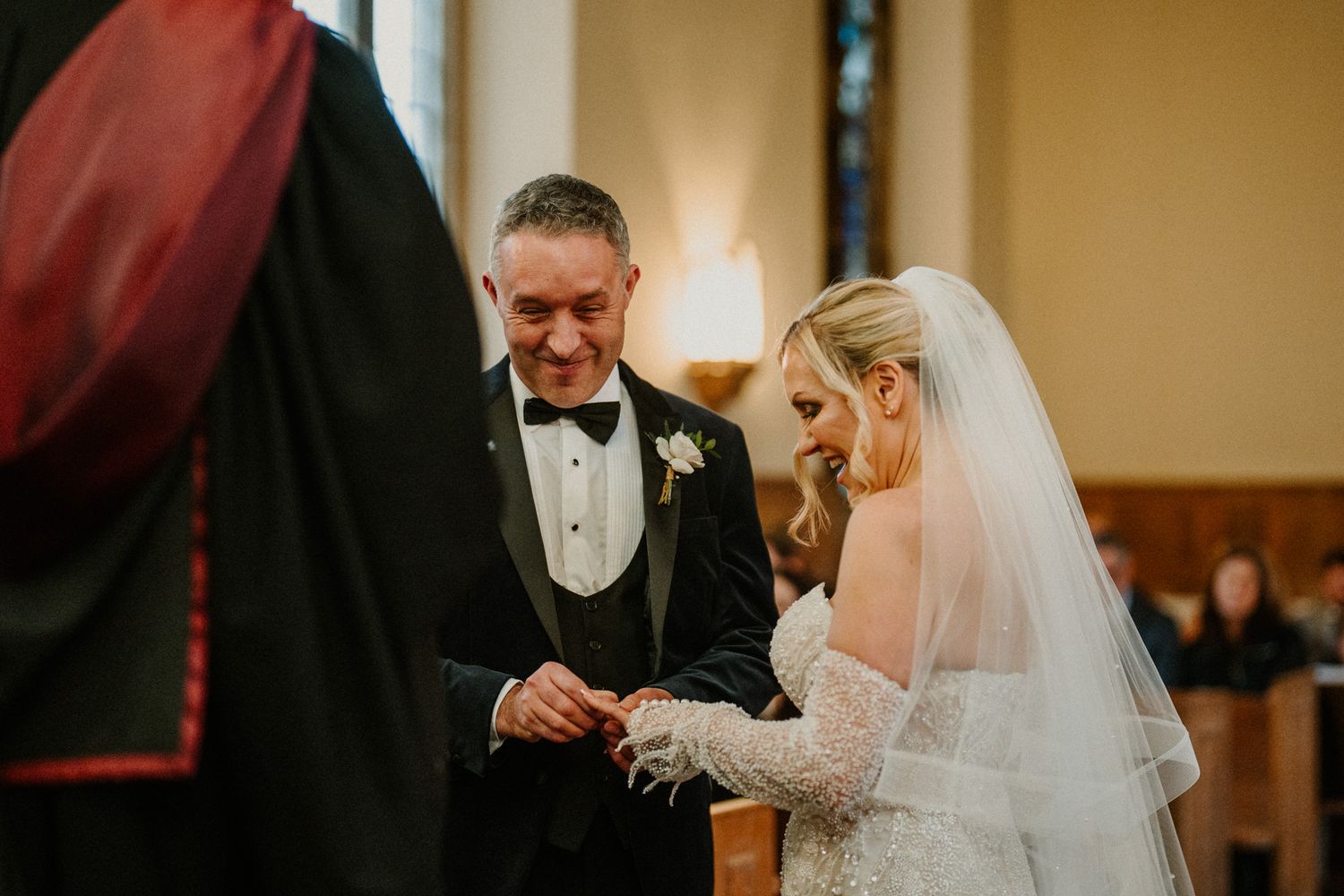 A couple exchanges rings during their wedding ceremony in a traditional church setting.
