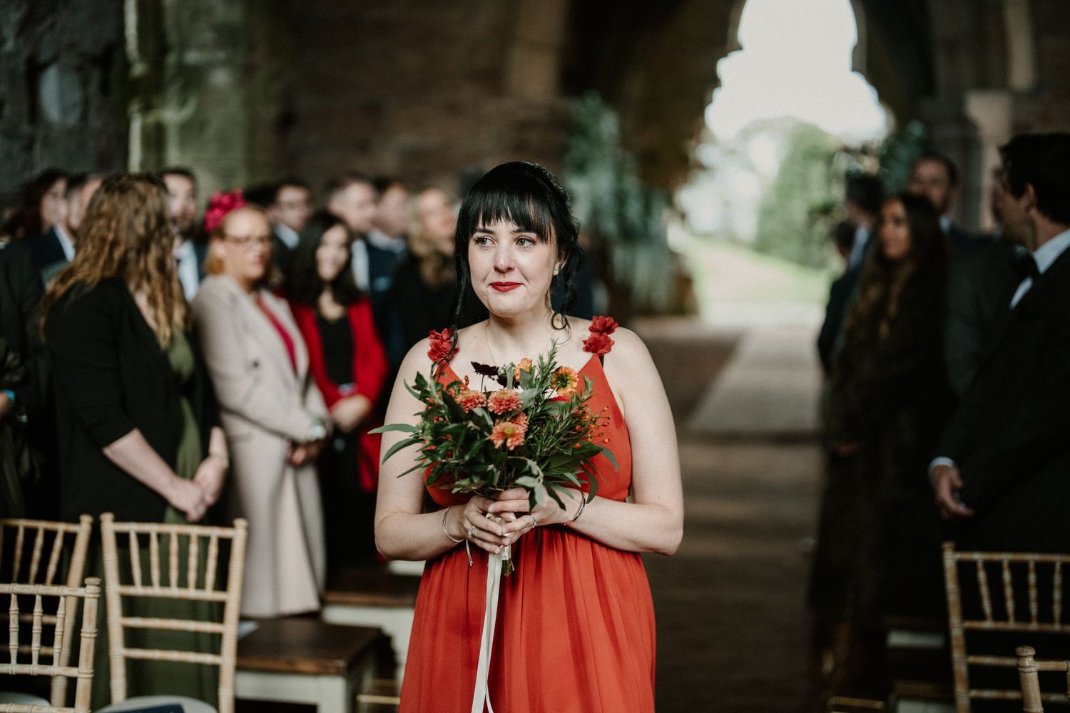 Wedding celebration in stone church features red bridesmaid dresses and elegant decor.