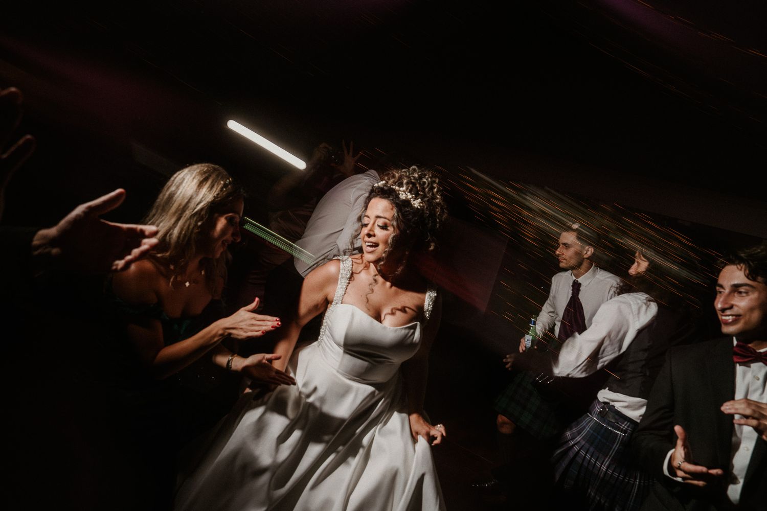 Dark and dramatic wedding reception scene with dancers silhouetted against ambient lighting.