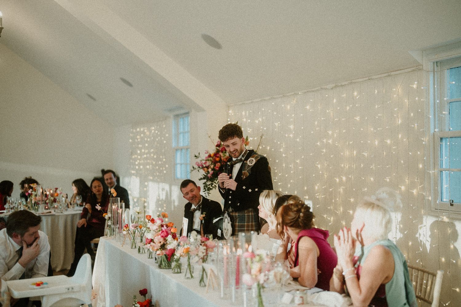 Wedding reception venue decorated with fairy lights and white table settings.