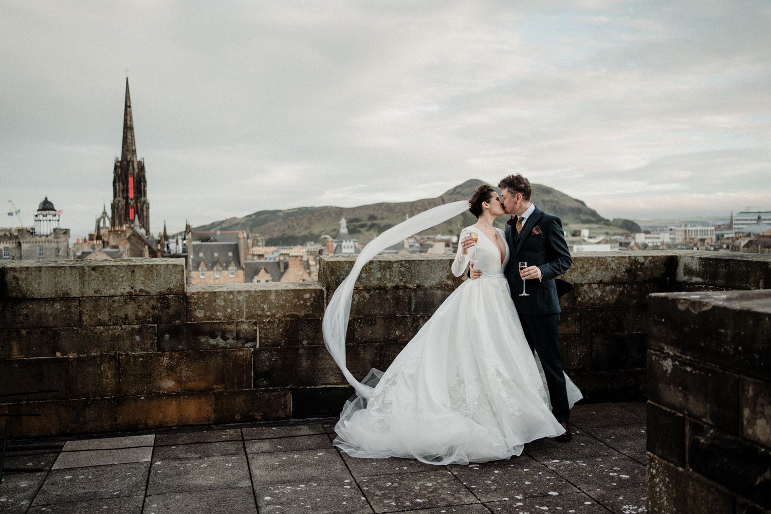 Dramatic wedding photos captured along Edinburgh Castle's historic walls with city views.