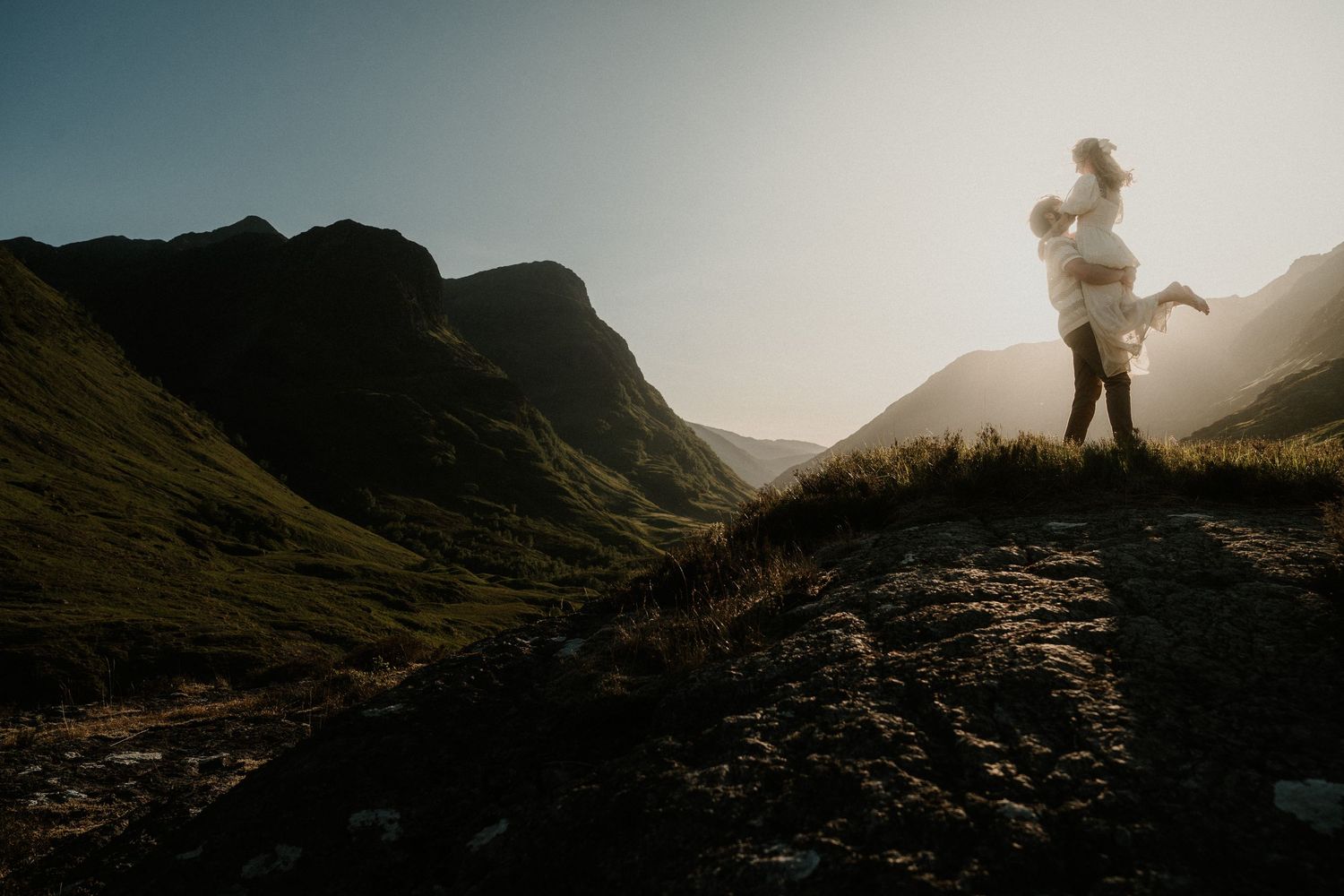 Silhouettes against dramatic mountain landscape at sunset creating romantic atmosphere.