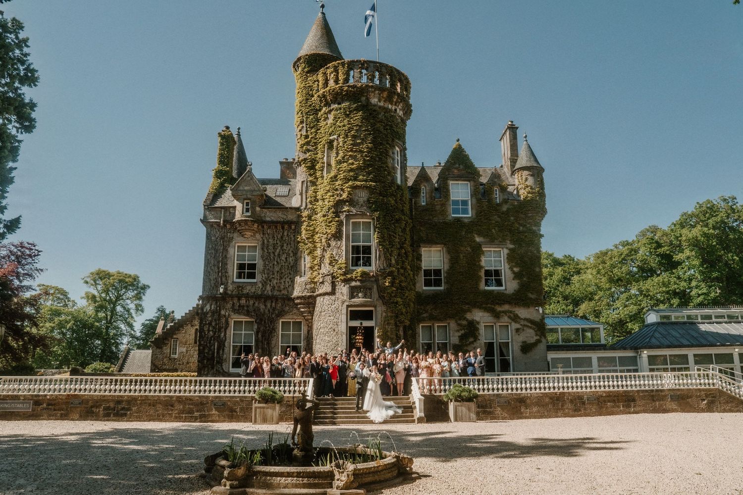 Panoramic view of a castle-style wedding venue with stone turrets against blue sky.