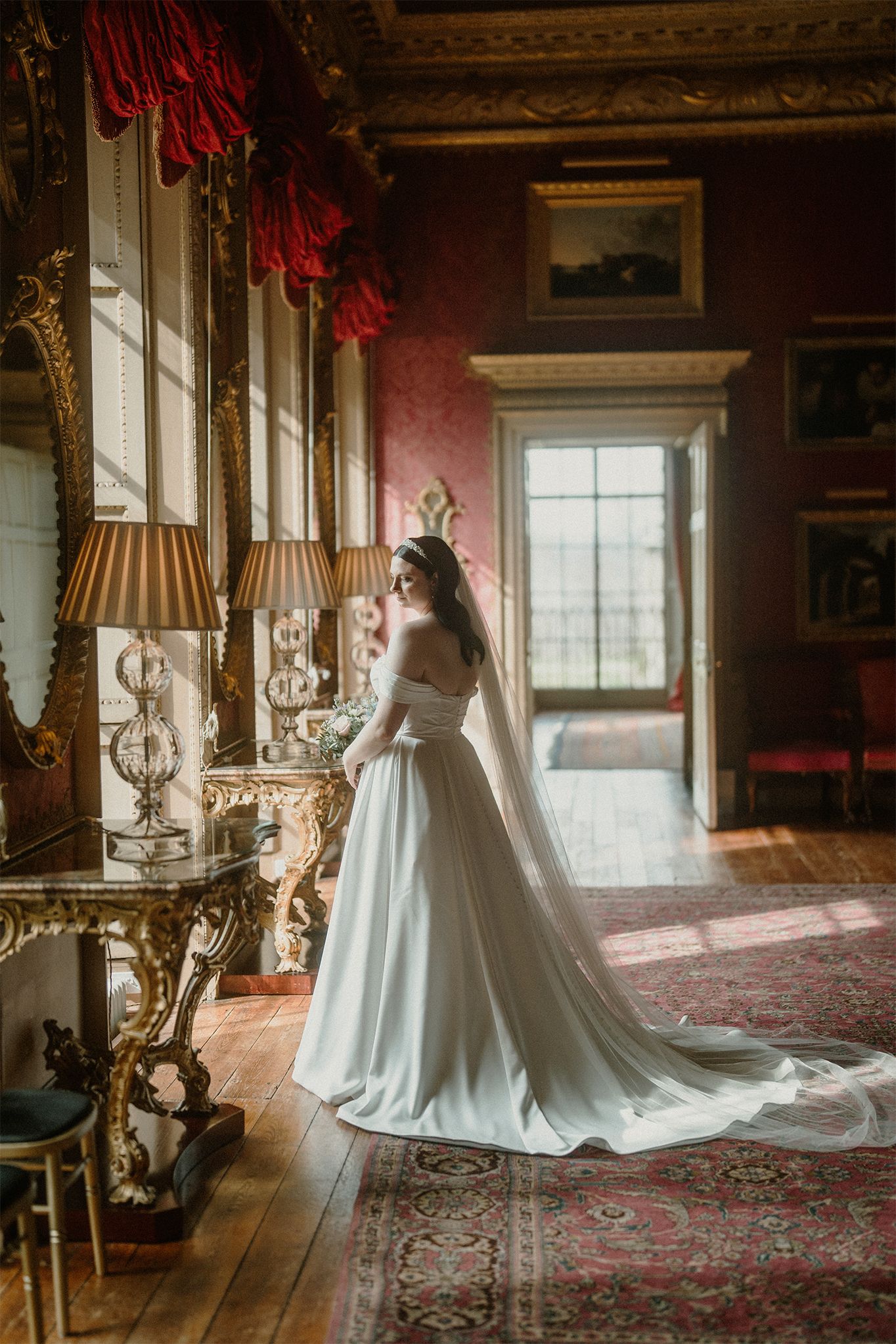 A dramatic bridal portrait in a luxurious historic room with ornate furnishings and natural light.