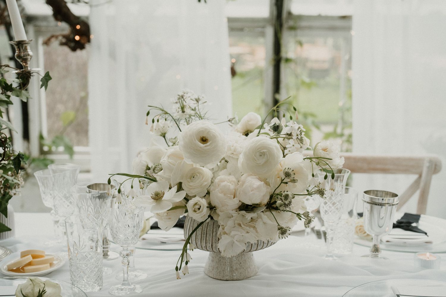 White floral centerpiece with roses in vintage vase on elegant wedding table.