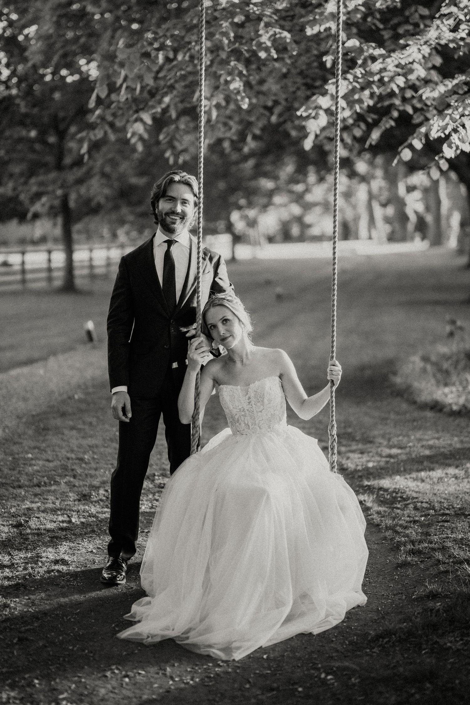 Black and white photo of a couple sharing a romantic moment on a tree swing.