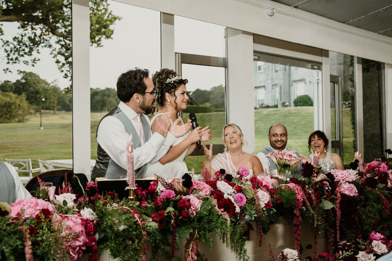 Wedding reception venue decorated with pink flowers and white columns.