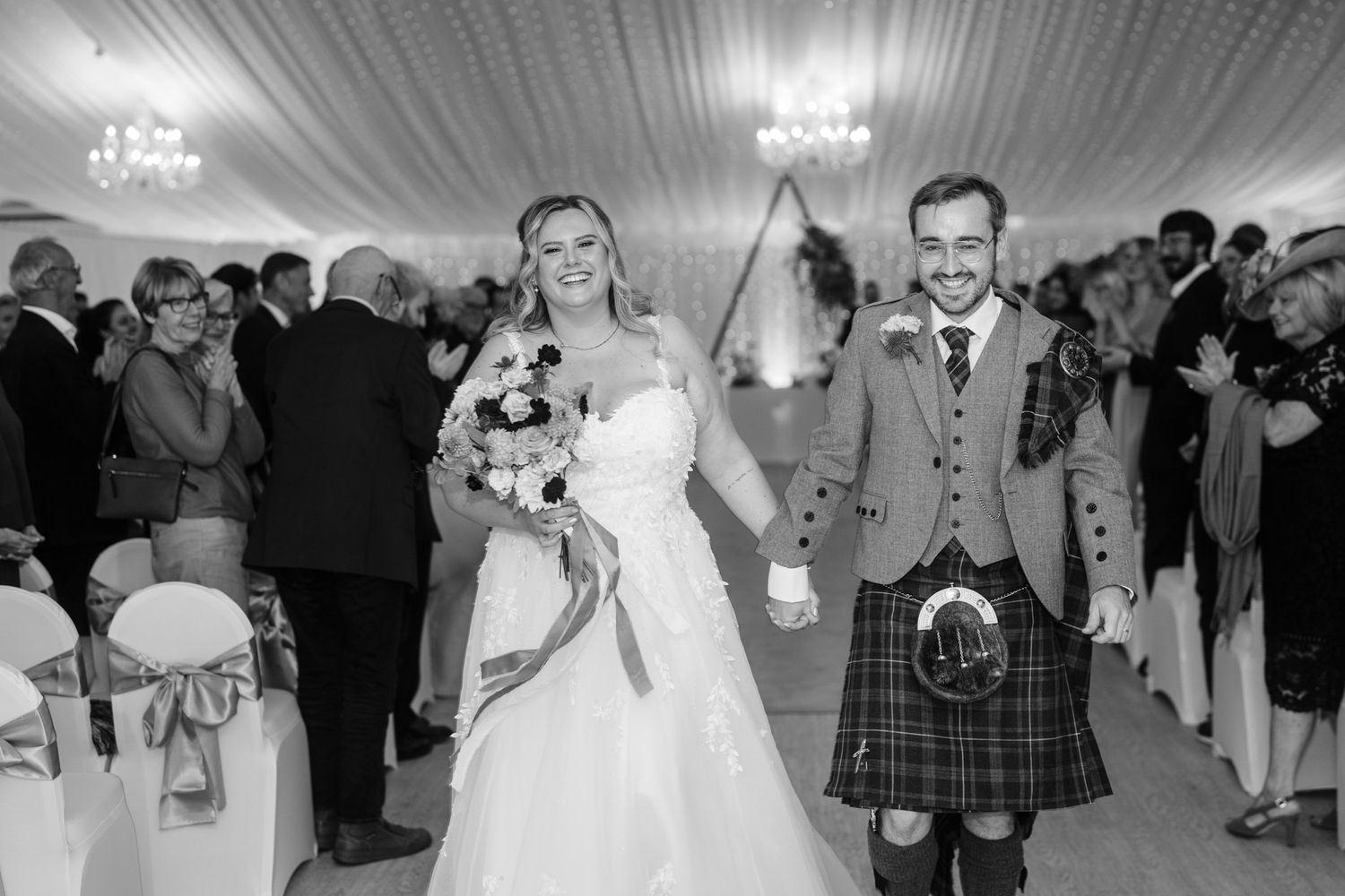 Black and white photo of wedding reception with guests dancing and celebrating.