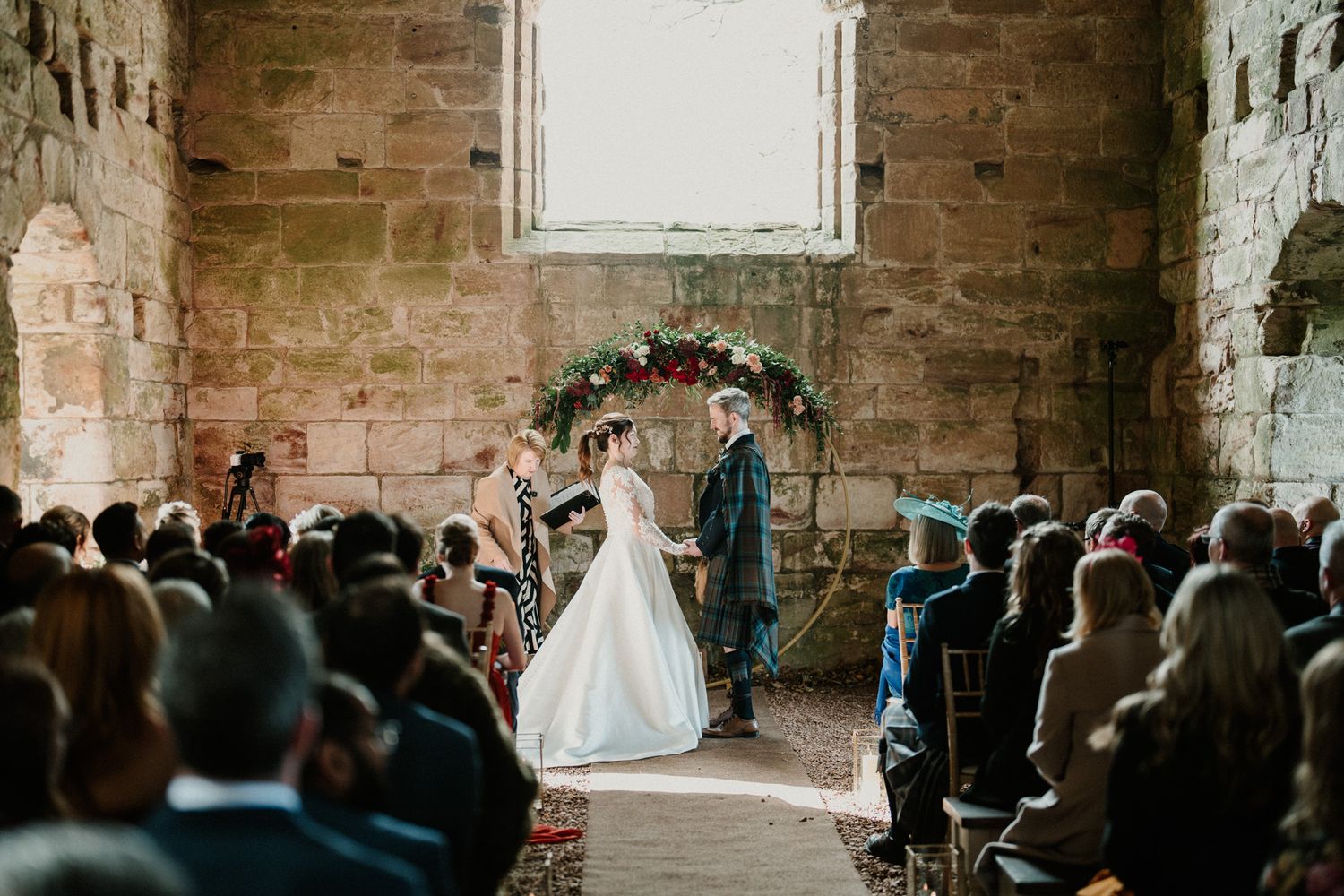 Wedding ceremony in progress inside historic stone church with gathered guests.