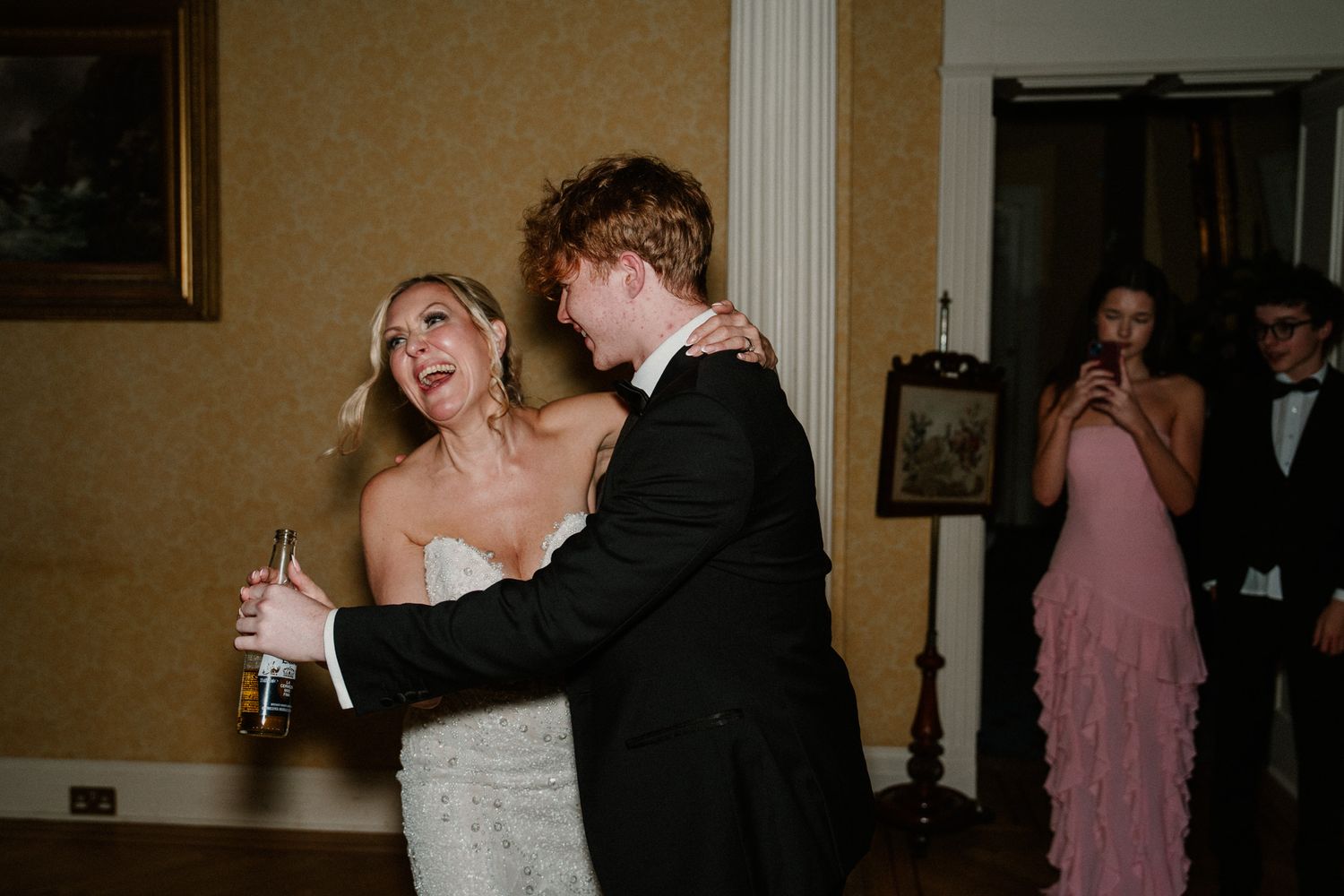 Elegant wedding reception with guests dancing and mingling in a warmly lit ballroom.