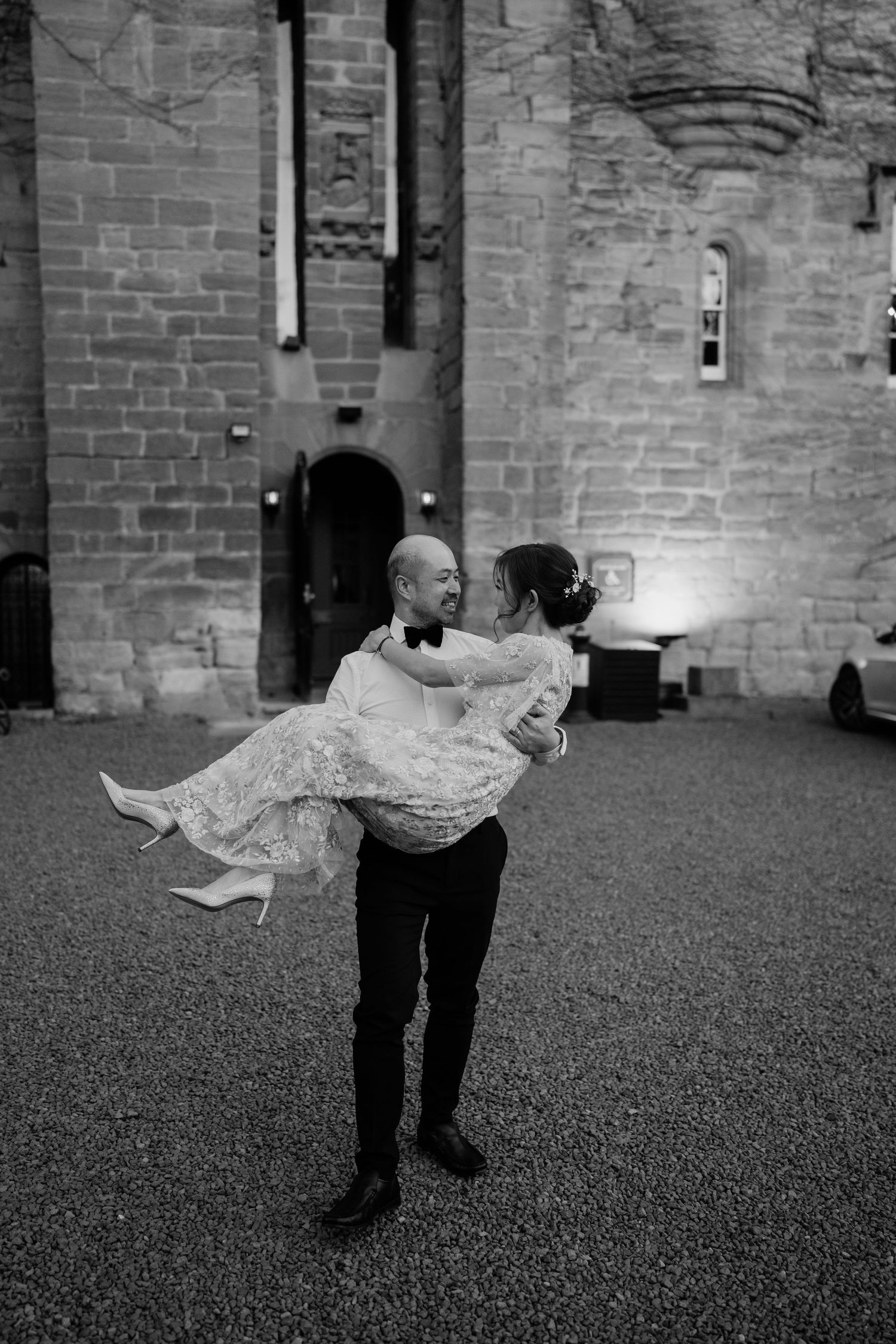 A dramatic black and white photo of a dance lift in front of stone walls.