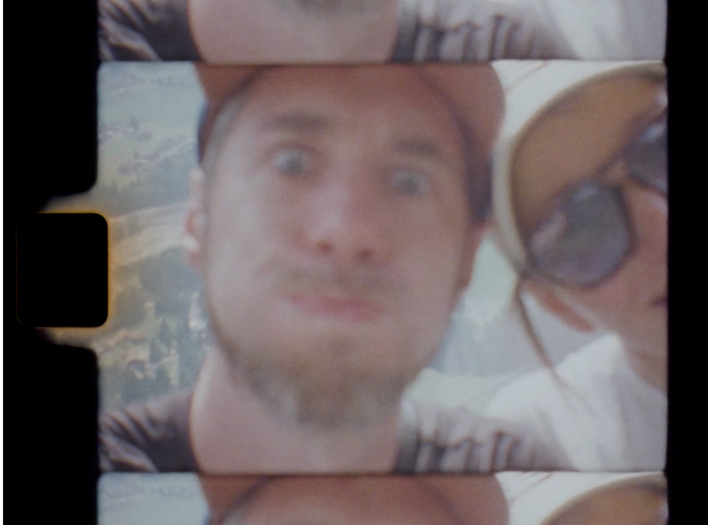 Close-up selfie of two people outdoors, one wearing sunglasses, captured on vintage film strip format.