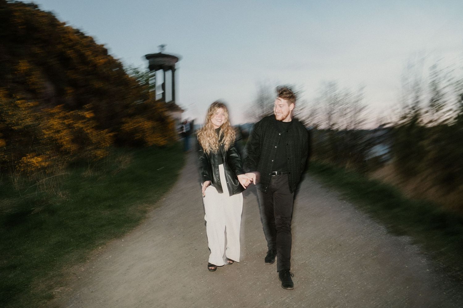 Couple walking hand in hand on a path at Calton Hill Edinburgh at twilight.
