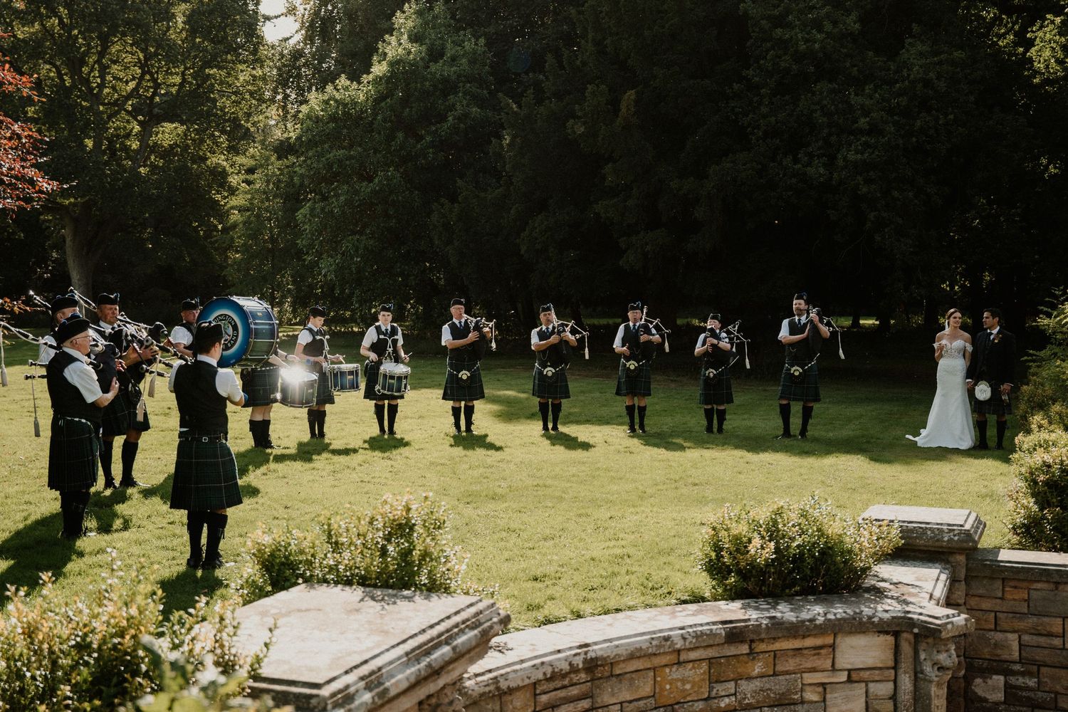 Wedding celebration with bagpipers performing on castle grounds.