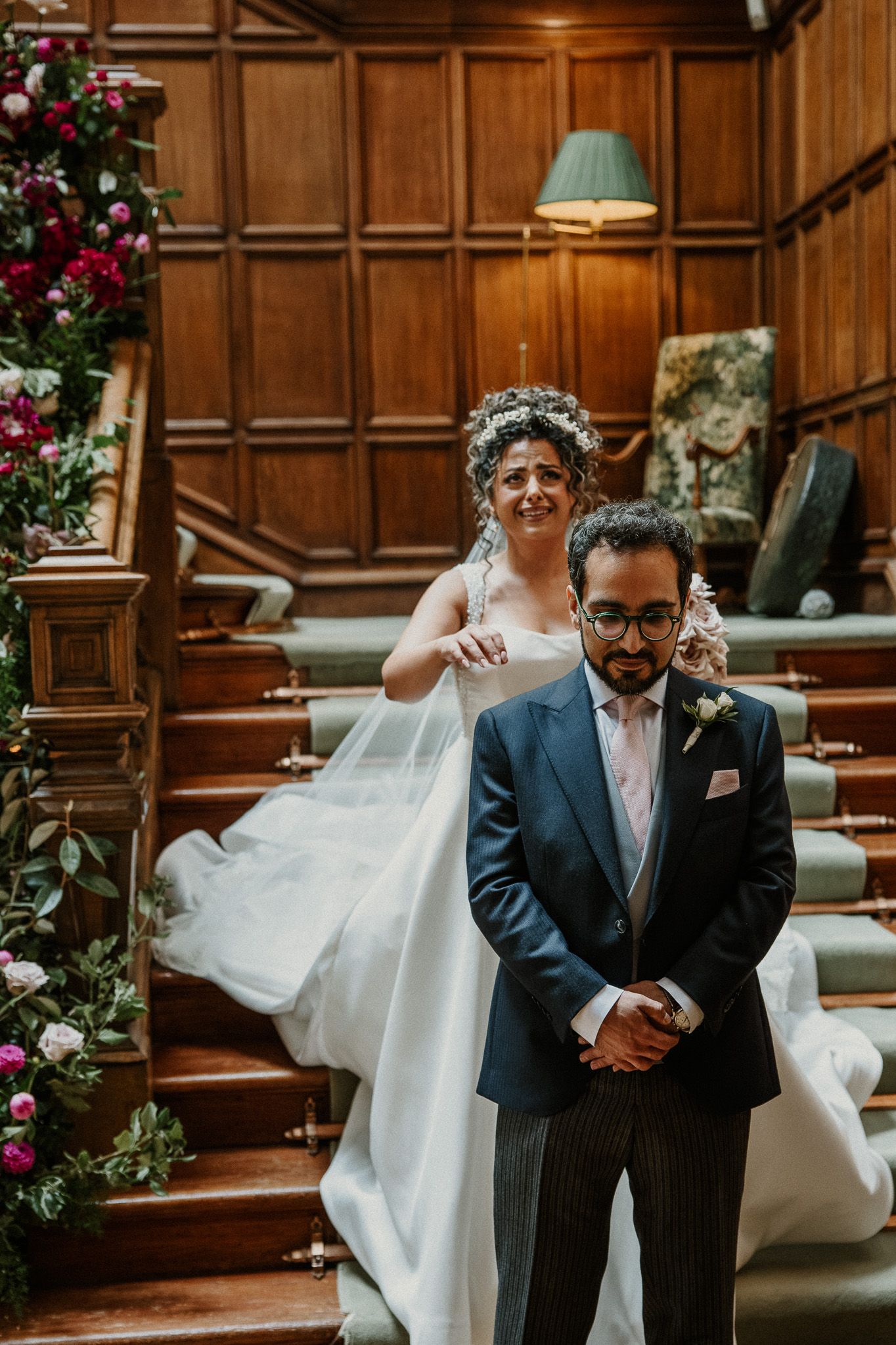 Elegant wedding ceremony in wood-paneled church adorned with pink and burgundy floral arrangements.