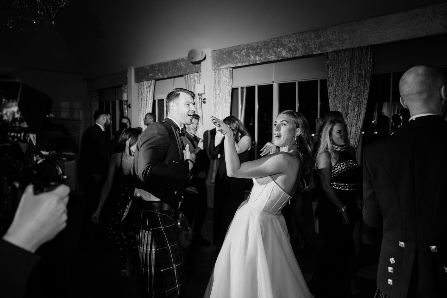 Black and white photo of a wedding reception dance floor with dramatic lighting effects.