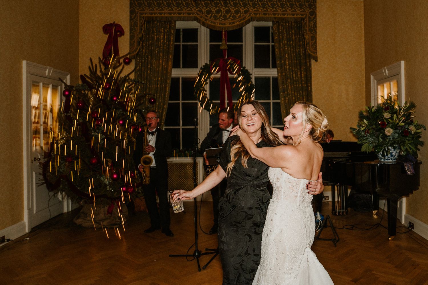 Couples dancing at an elegant wedding reception in a grand ballroom with ornate decor.