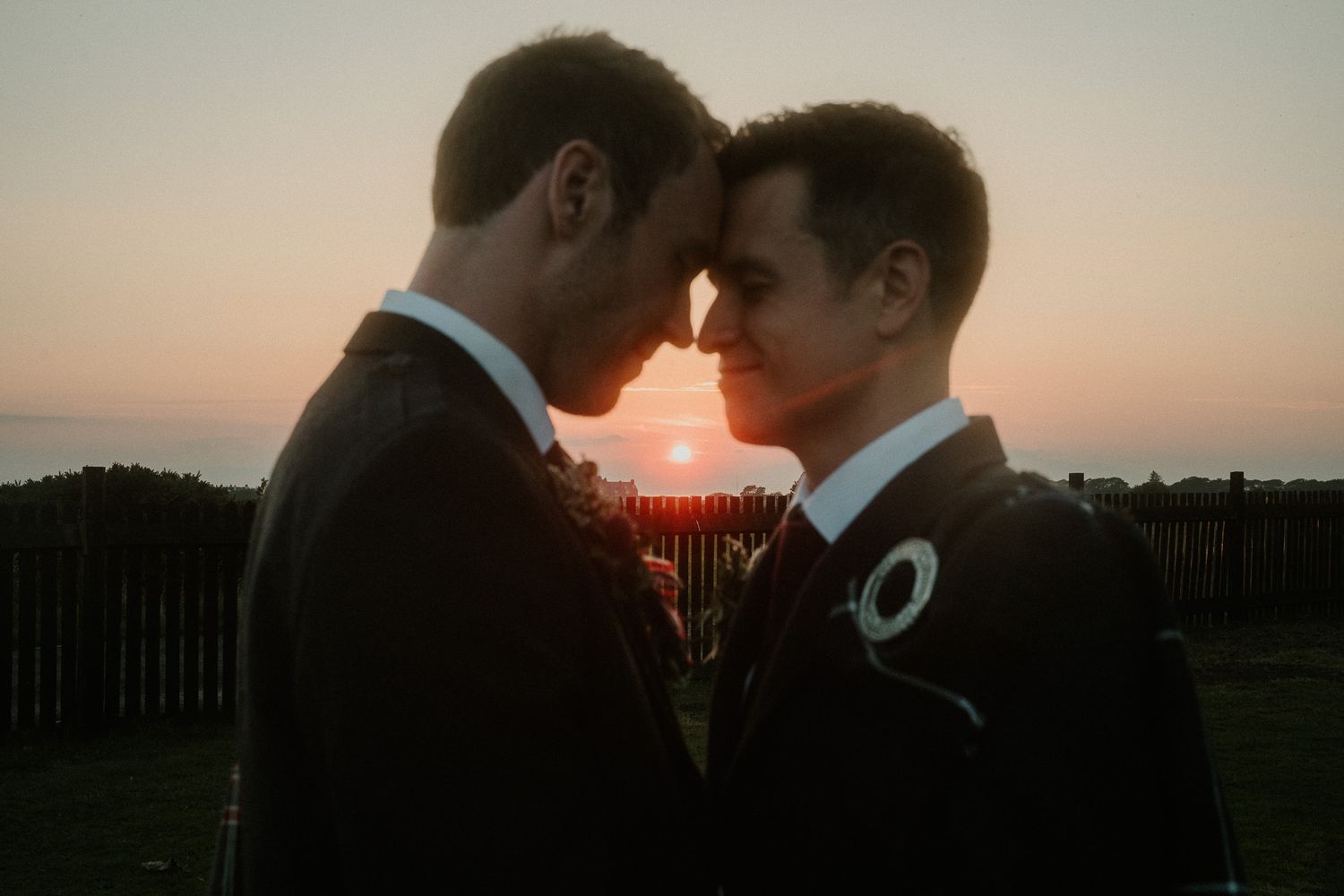 Silhouettes of couple against dramatic sunset sky with warm orange glow.