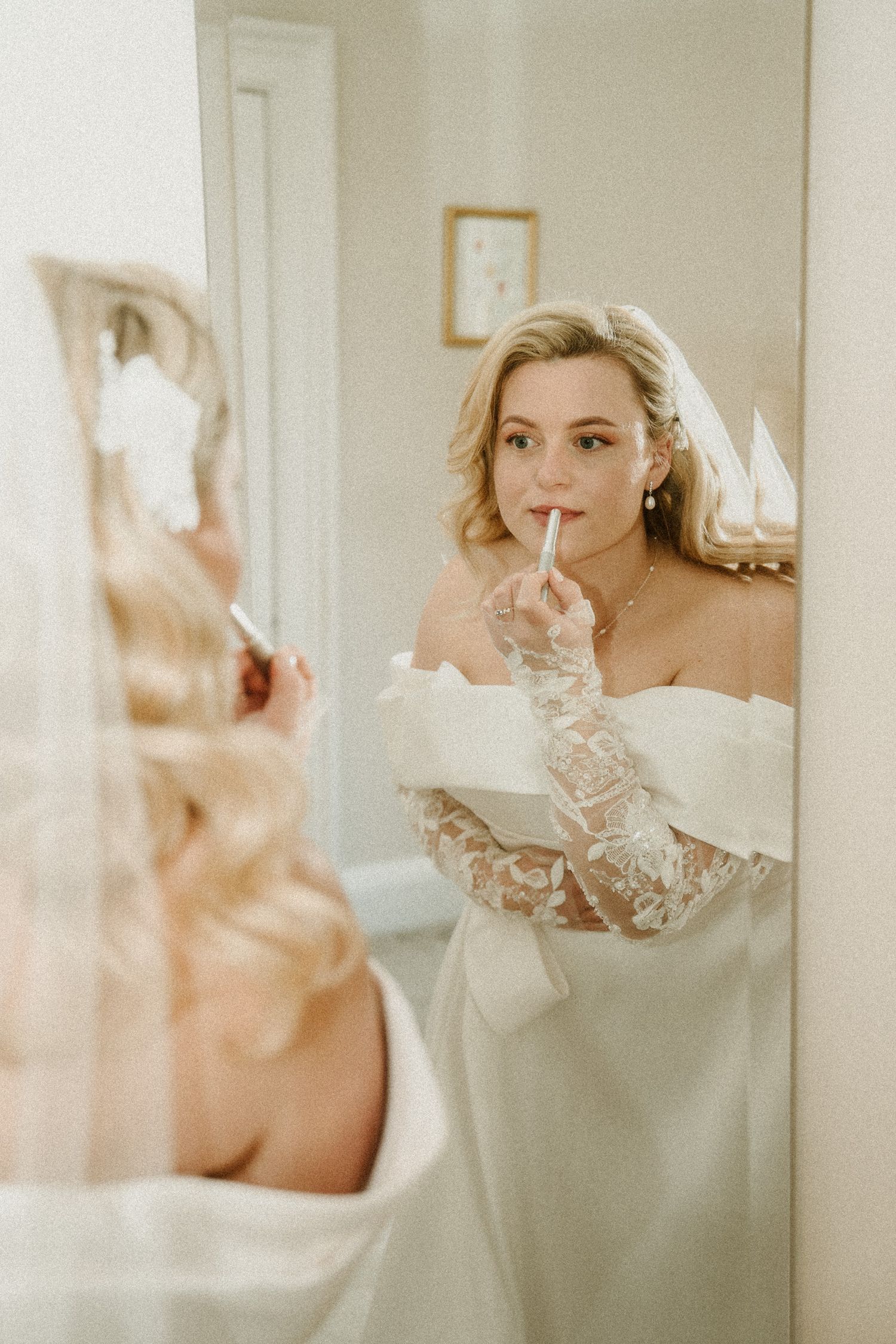 Elegant bridal portrait reflected in mirror showing off-shoulder wedding dress details.