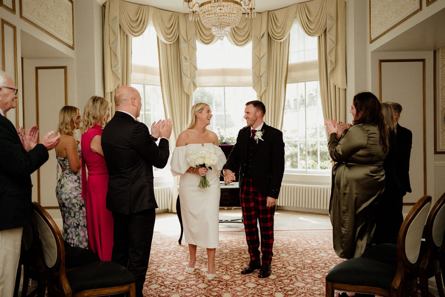 Wedding party poses in an ornate room with classic architectural details and natural lighting.