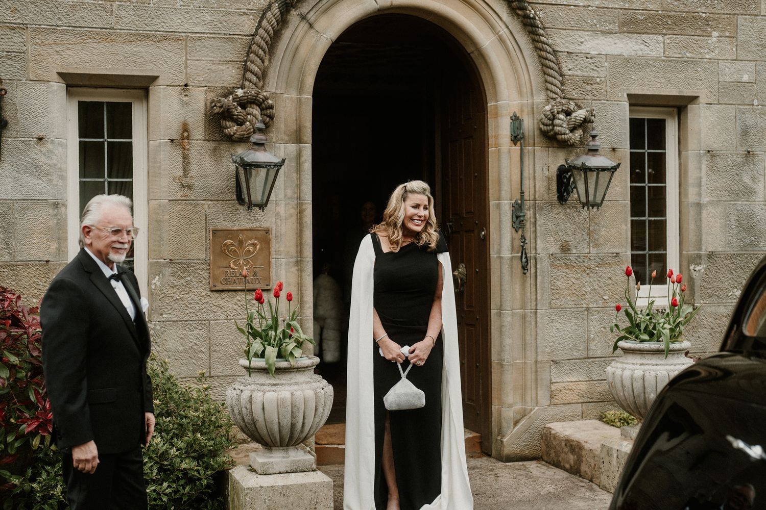 Stone mansion entrance decorated with elegant urns and lanterns for wedding ceremony.
