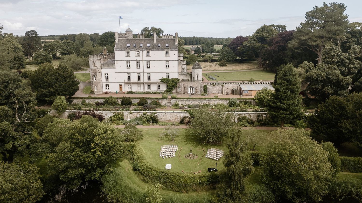 Aerial view of majestic Scottish castle estate with manicured grounds and gardens.