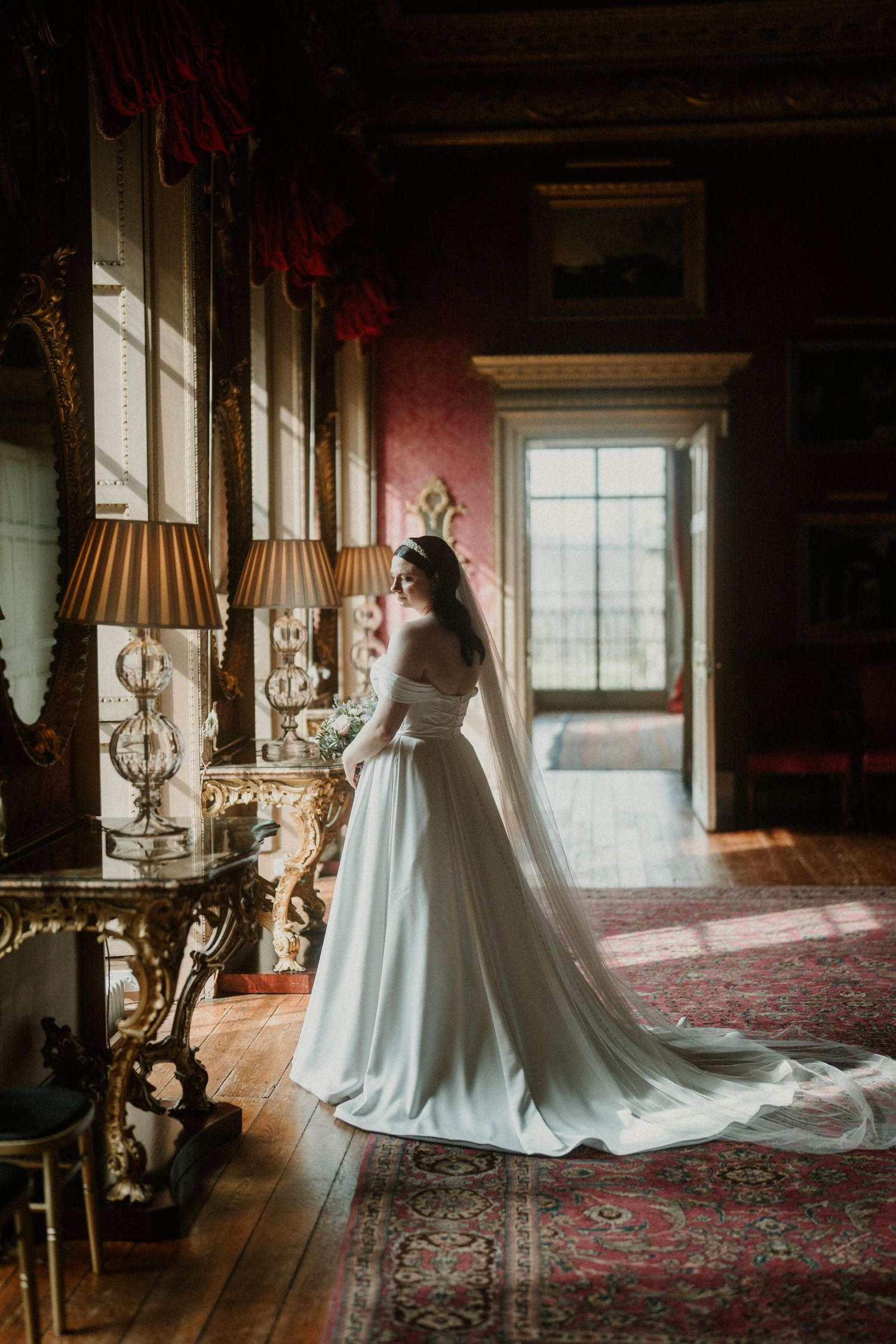 Wedding dress silhouettes against dramatic lighting in opulent room at Hopetoun House in Scotland.