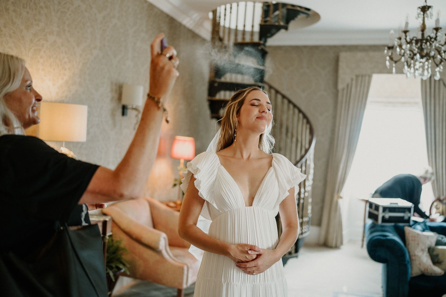 Elegant bridal preparation room with chandelier and natural window light.