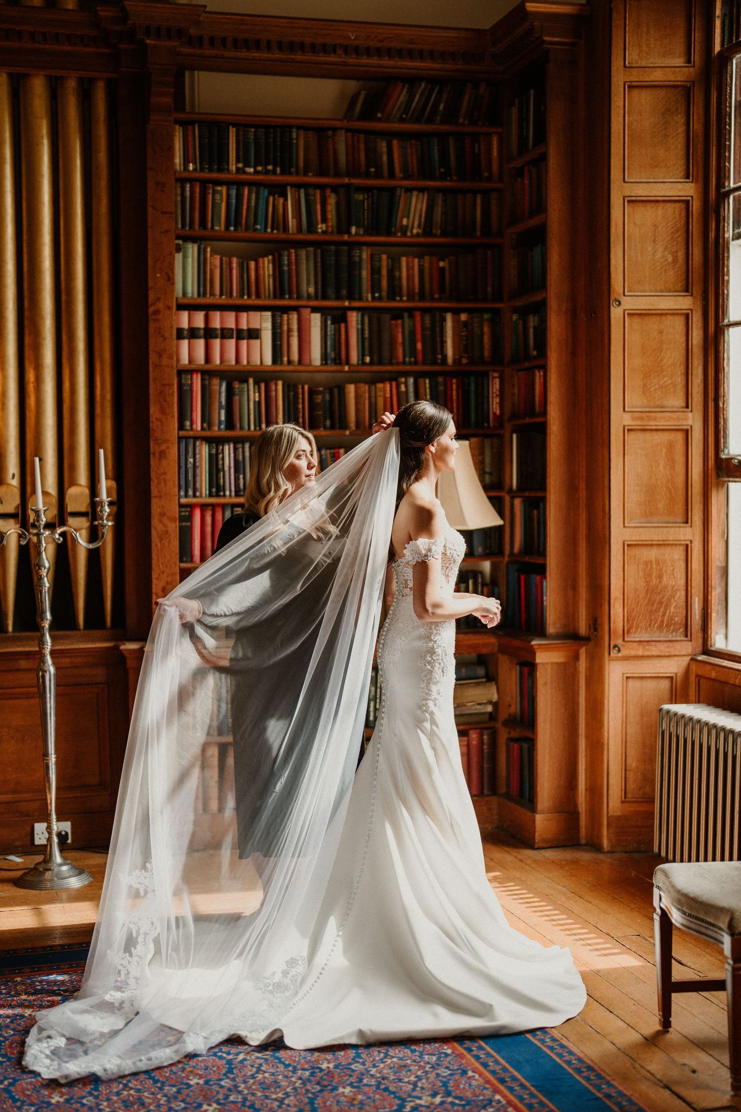 White wedding dresses with flowing veils displayed in an elegant wood-paneled library.