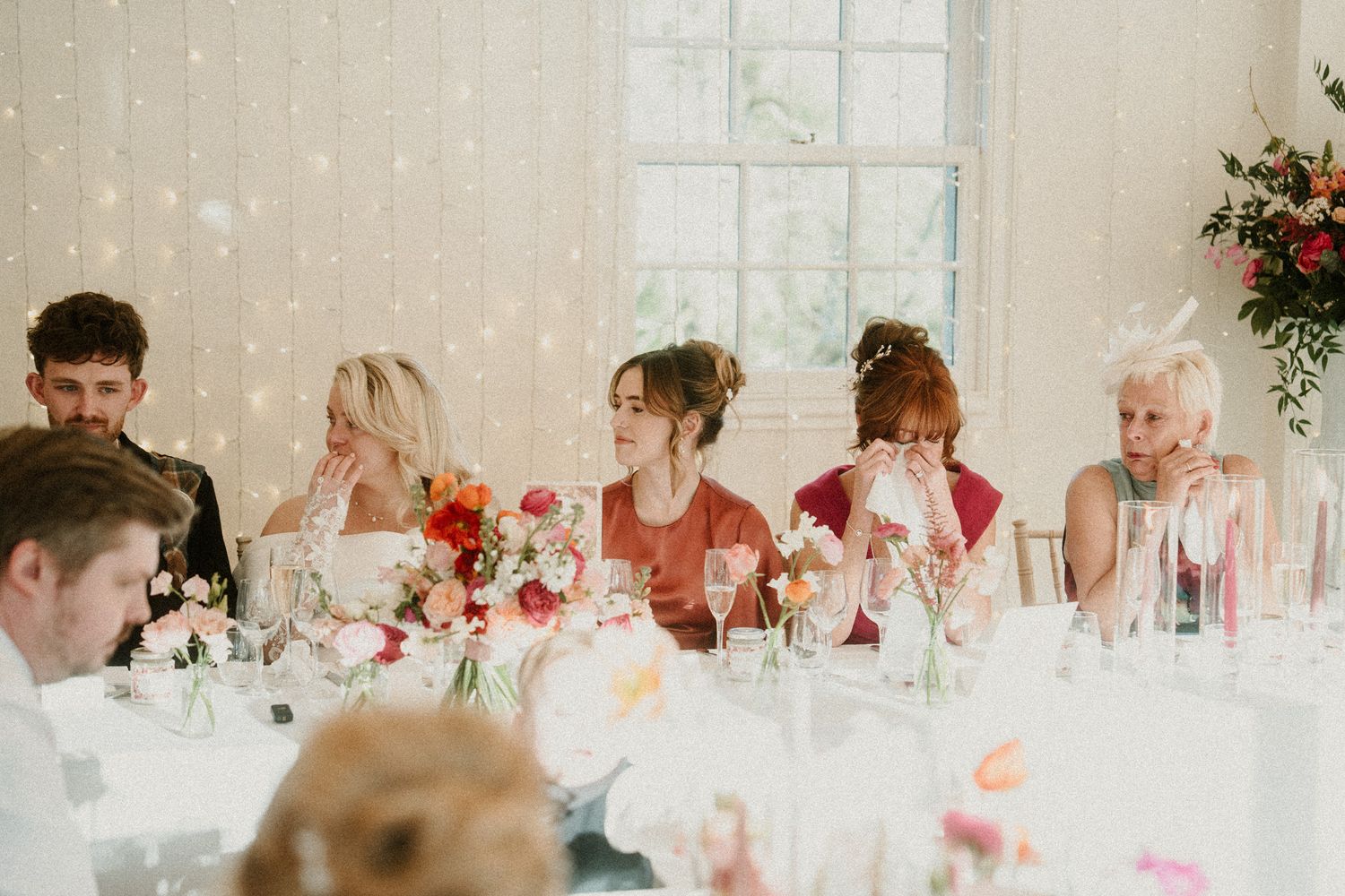 Wedding guests enjoying a celebration at decorated tables with floral centerpieces.